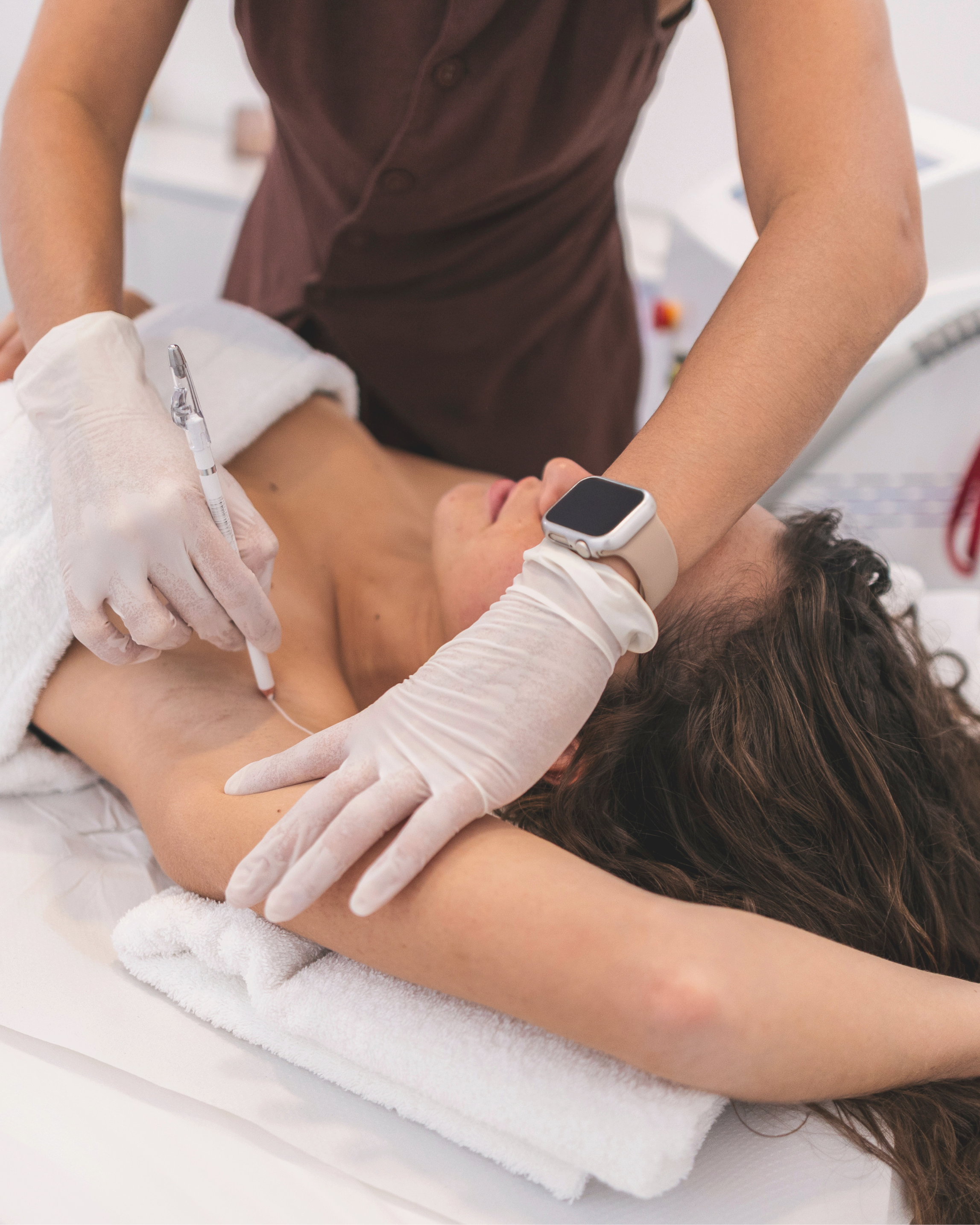A woman getting electrolysis. The electrolysis specalist is wearing gloves and has a smartwatch on their wrist.