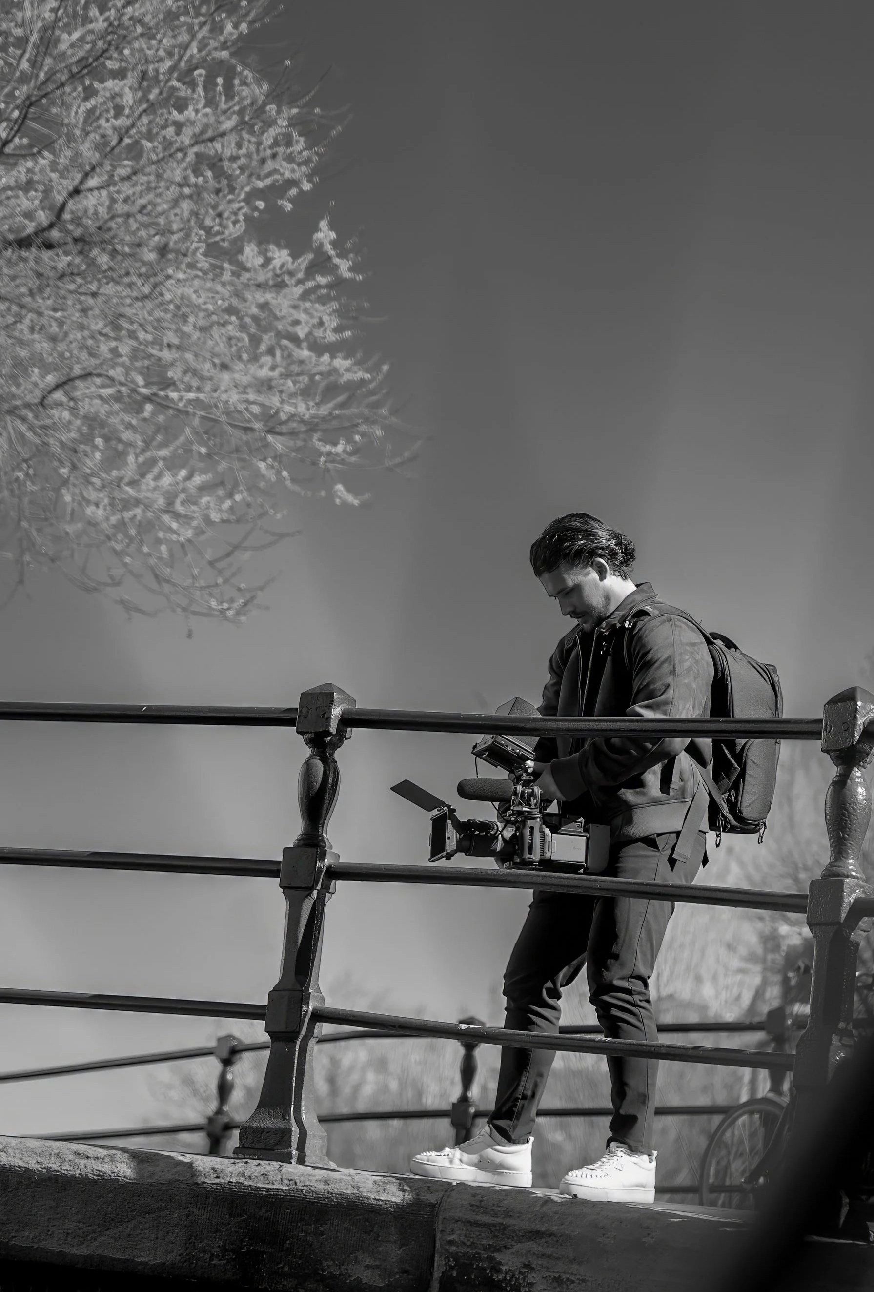 Man met een rugzak die op een brug staat en een camera vasthoudt