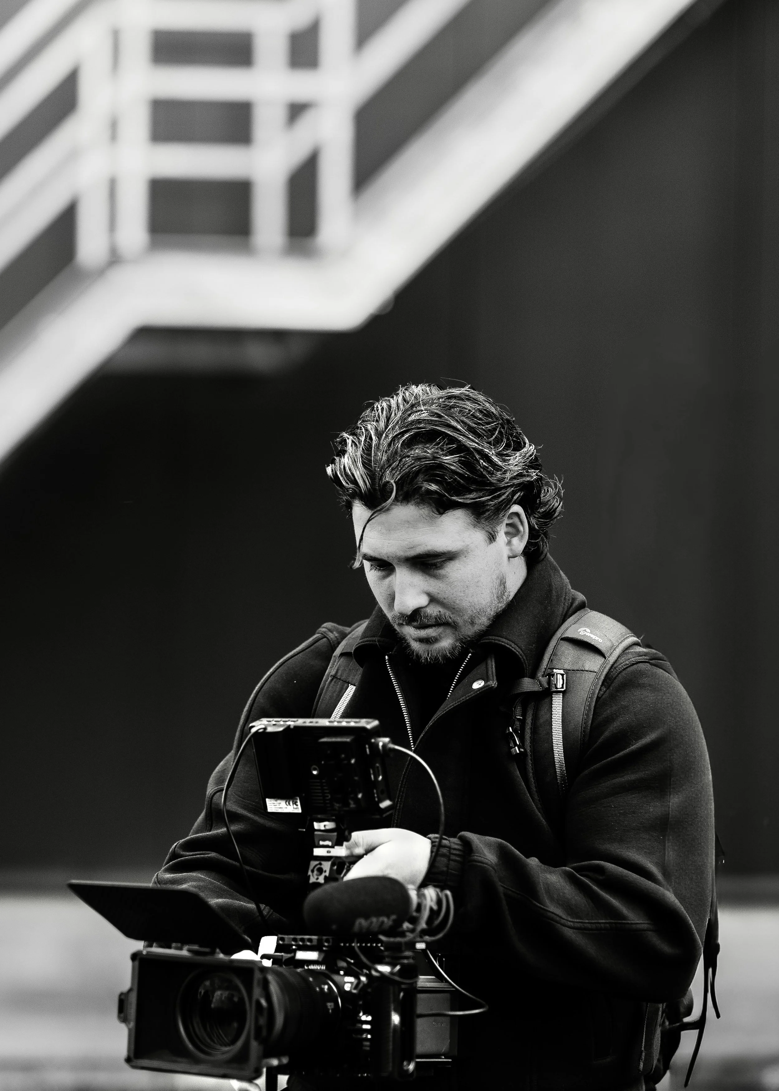 Man met een camera en uitrusting, zwart-wit foto.