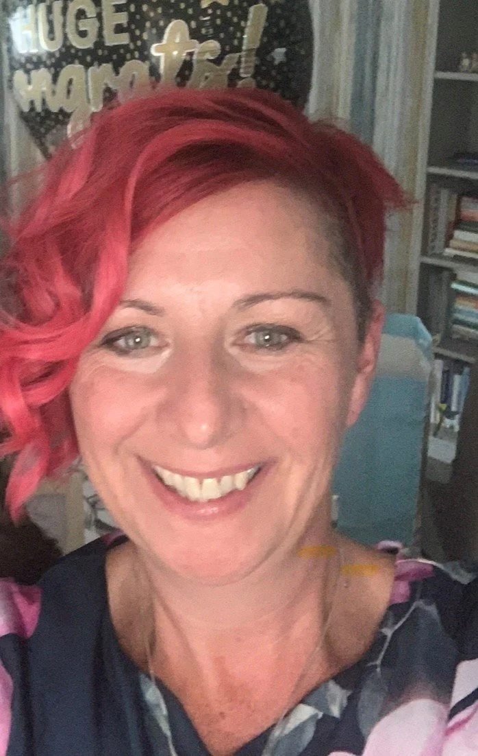 Narissa, smiling warmly at the camera with short, wavy red hair.