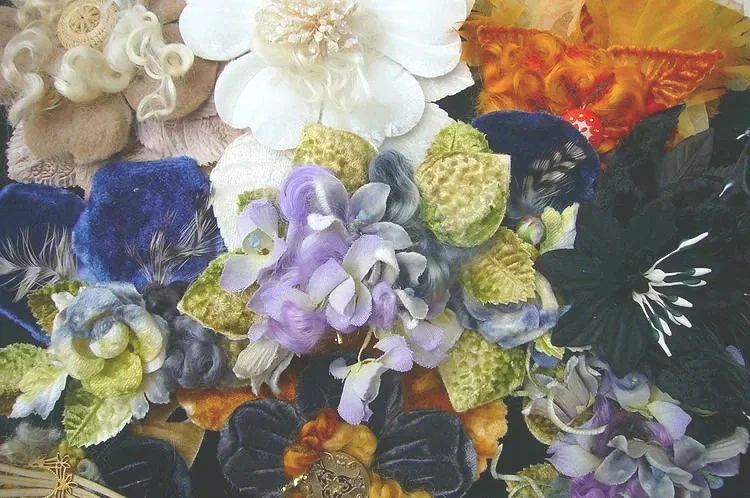 Colorful silk or fabric flowers in purple, green, black, orange, and white, likely decorative, arranged tightly together.