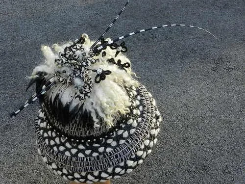 A decorative spherical object resembling a fishing bobber, decorated with various black and white patterns and materials, on a paved surface.
