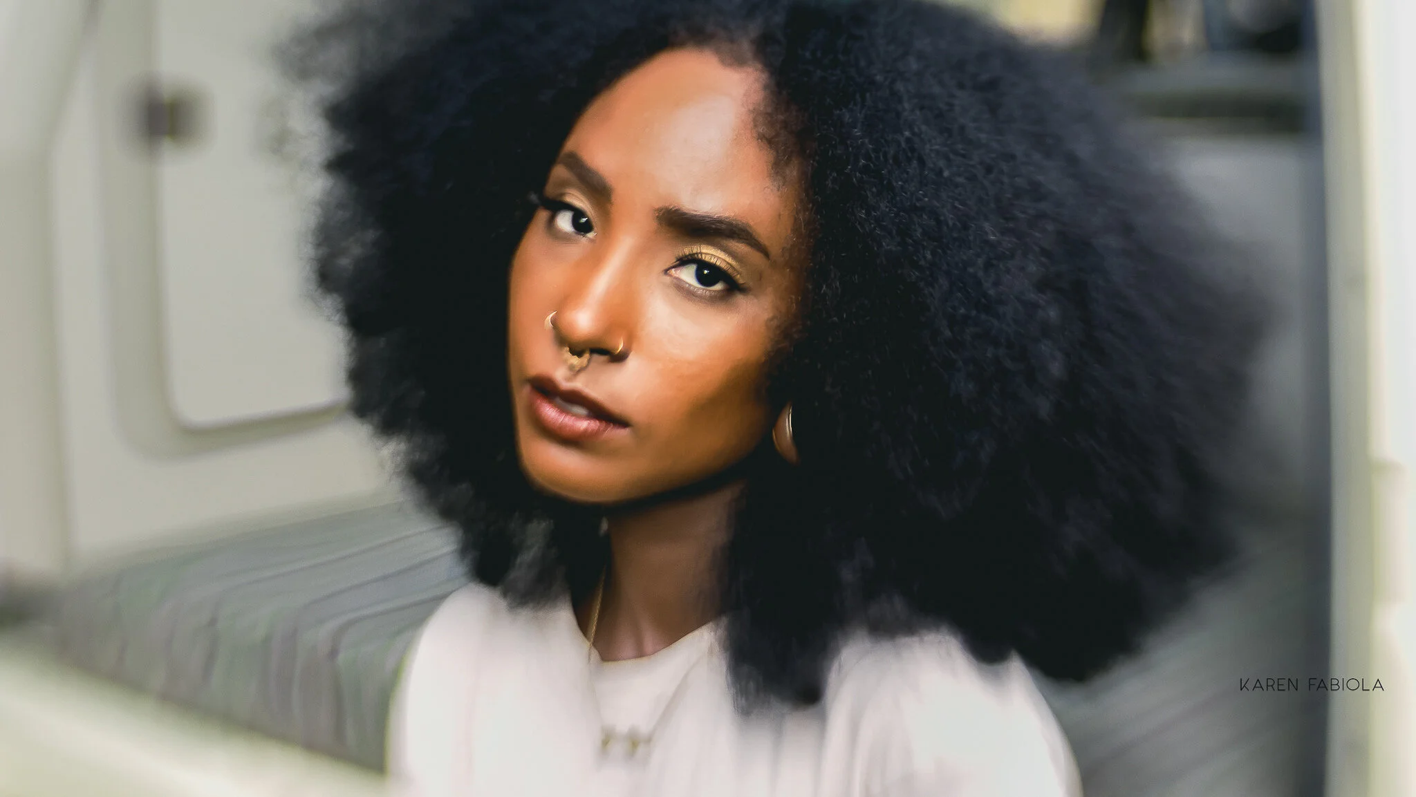 Mujer con afro voluminoso mirando a la cámara de perfil, con una presencia elegante y estilo fashion.