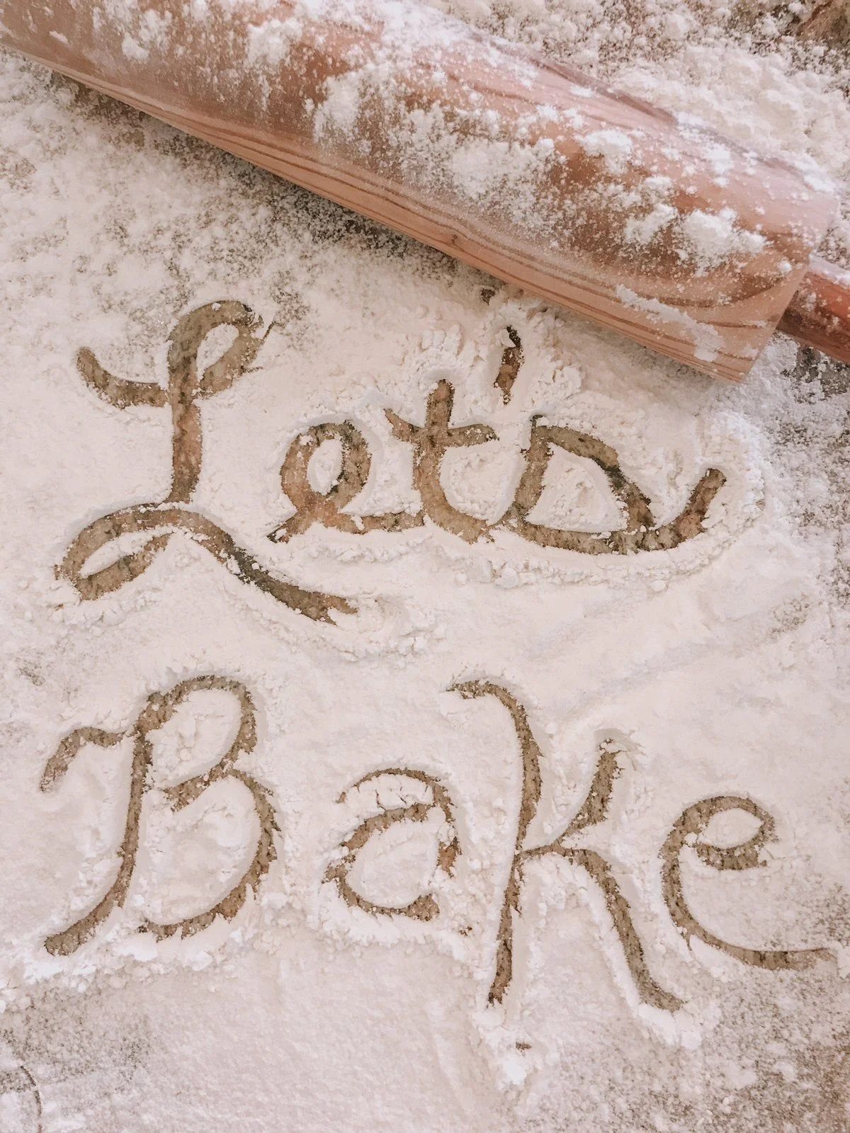 Flour with the words 'You are loved' written in it, next to a rolling pin.