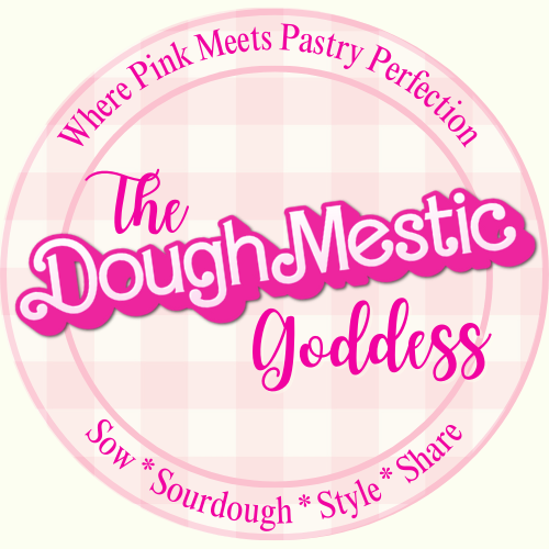 A circular logo with a pink and white checkered background. It features pink text reading "The Dough-Mestic Goddess" with a dark pink outline. Surrounding the main text is the phrase "Where Pink Meets Pastry Perfection" at the top and "Sow * Sourdough * Style * Share" at the bottom, all in pink.