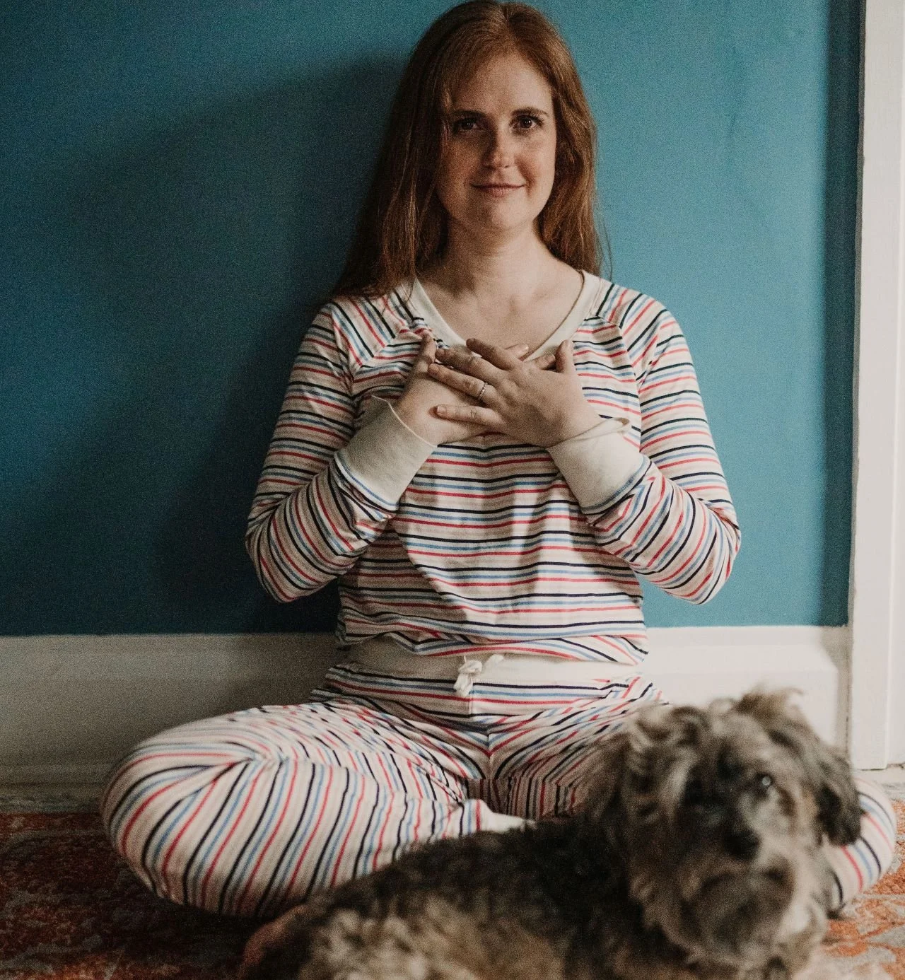 Christie sits with hands at heart center with Louis the dog