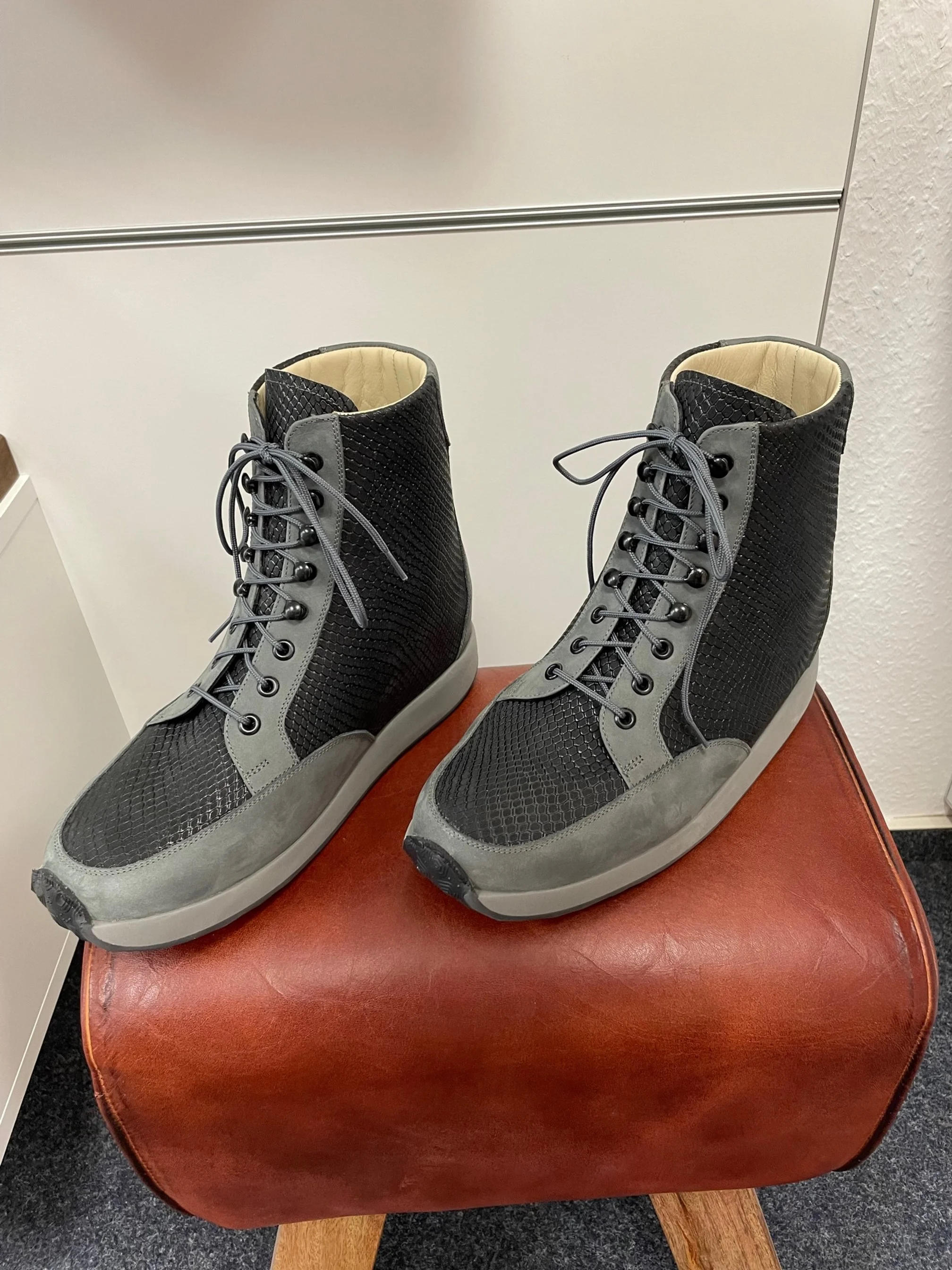 Ein Paar schwarze und graue High-Top-Sneaker auf einem roten Hocker