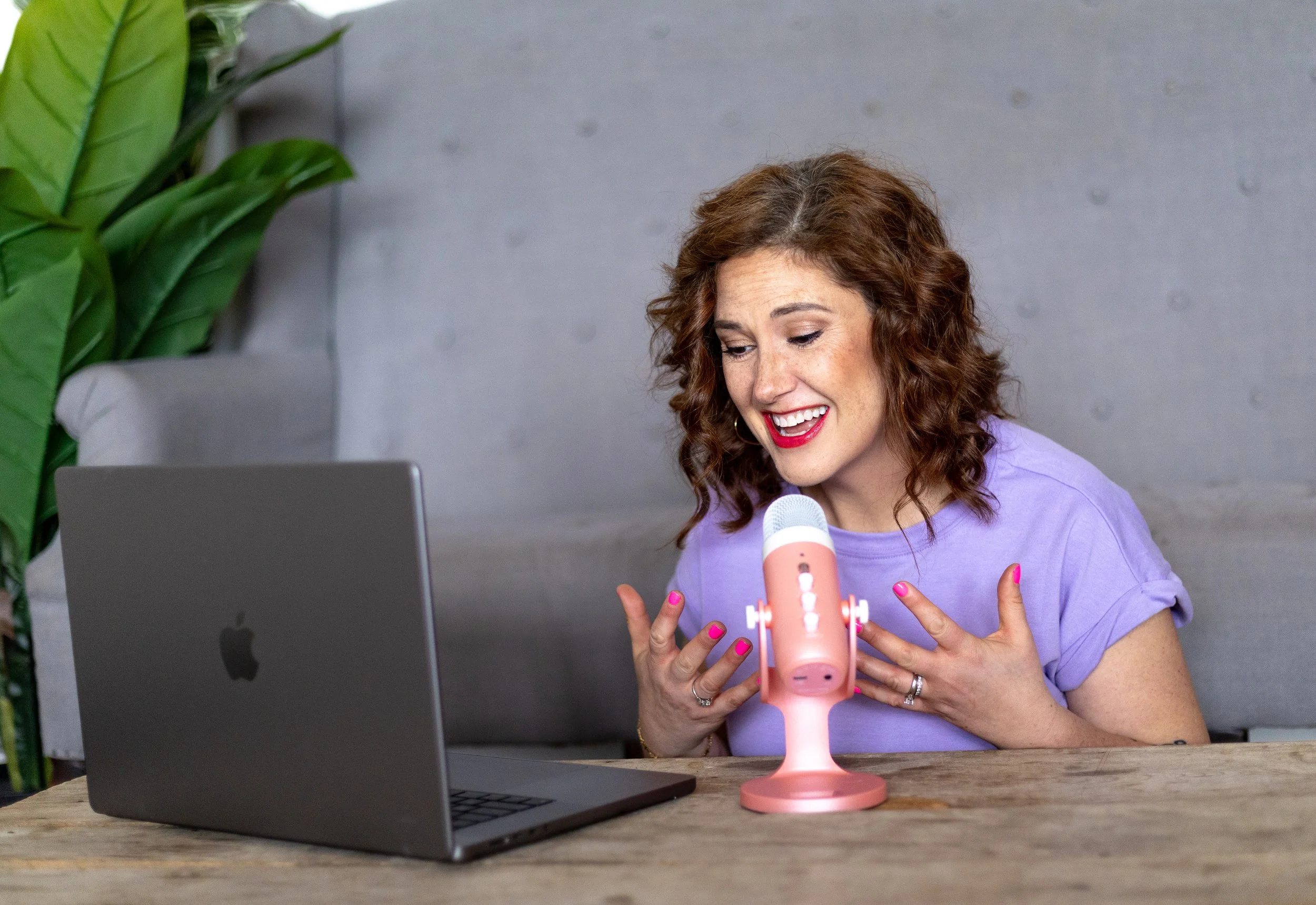 Woman hosting a grief support podcast with a microphone and laptop, sharing stories of hope after child loss