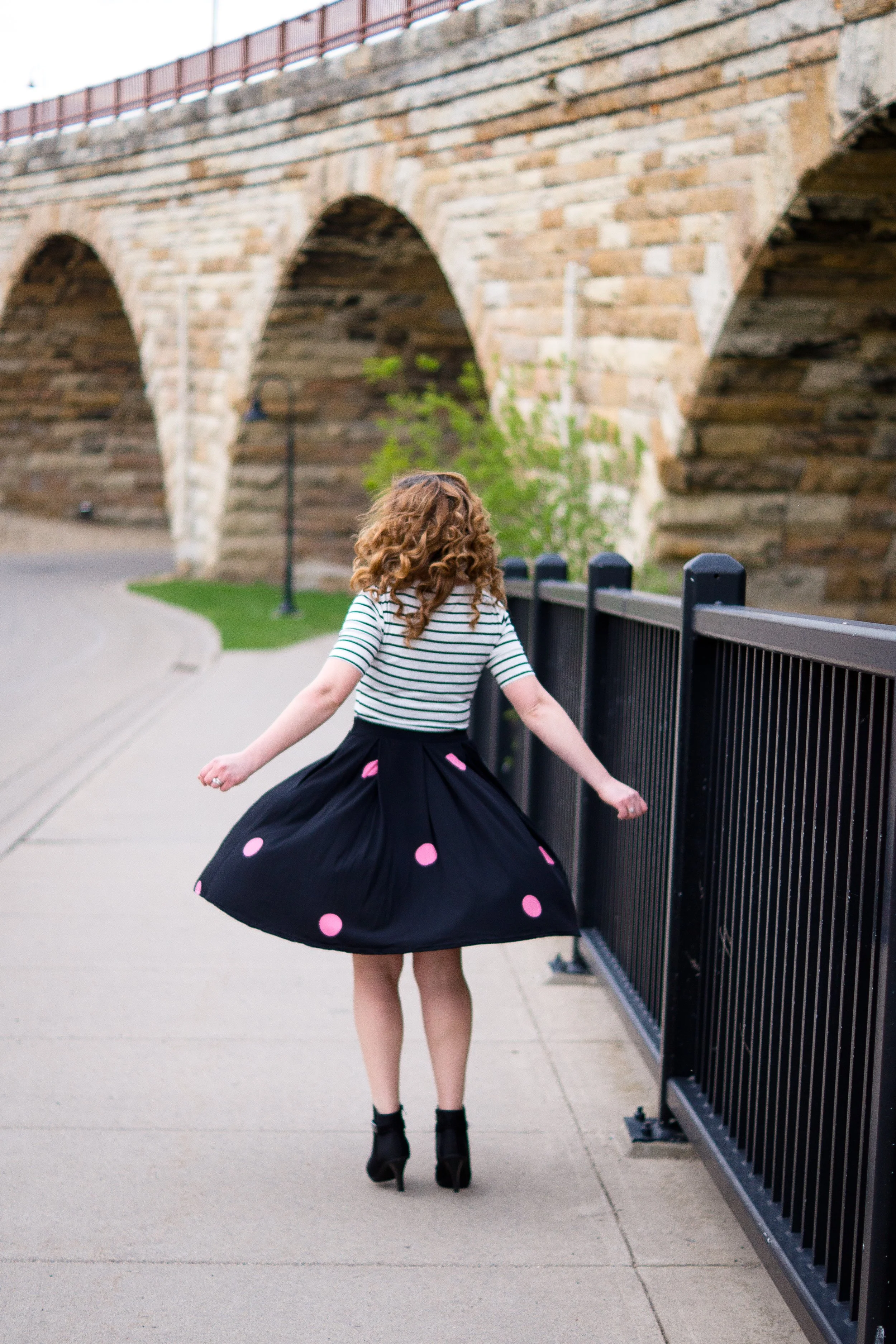 Woman twirling outdoors near a bridge, representing encouragement and hope for grieving mothers after child loss