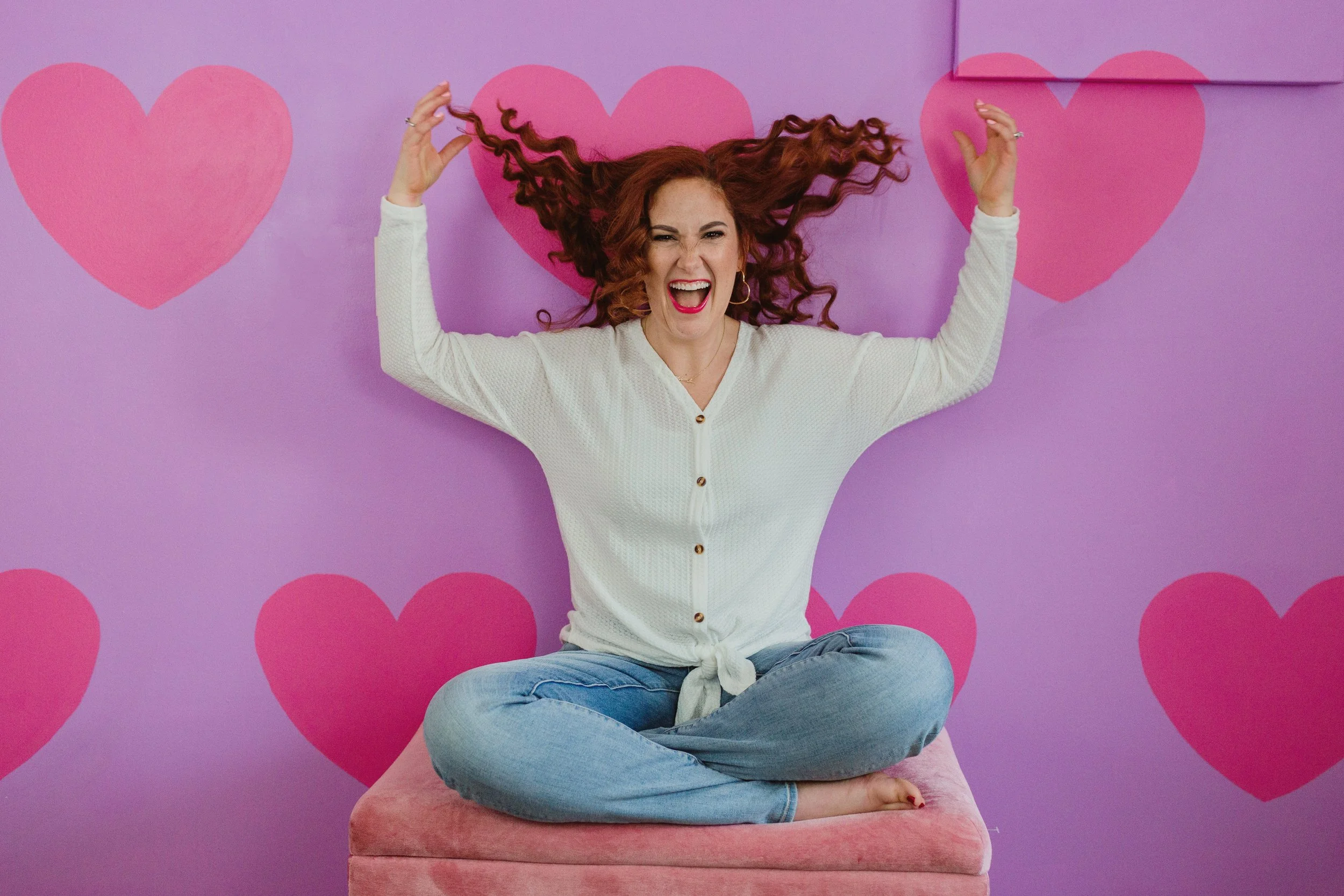 Woman smiling in a bright room with heart decorations, representing encouragement and hope for grieving mothers after child loss