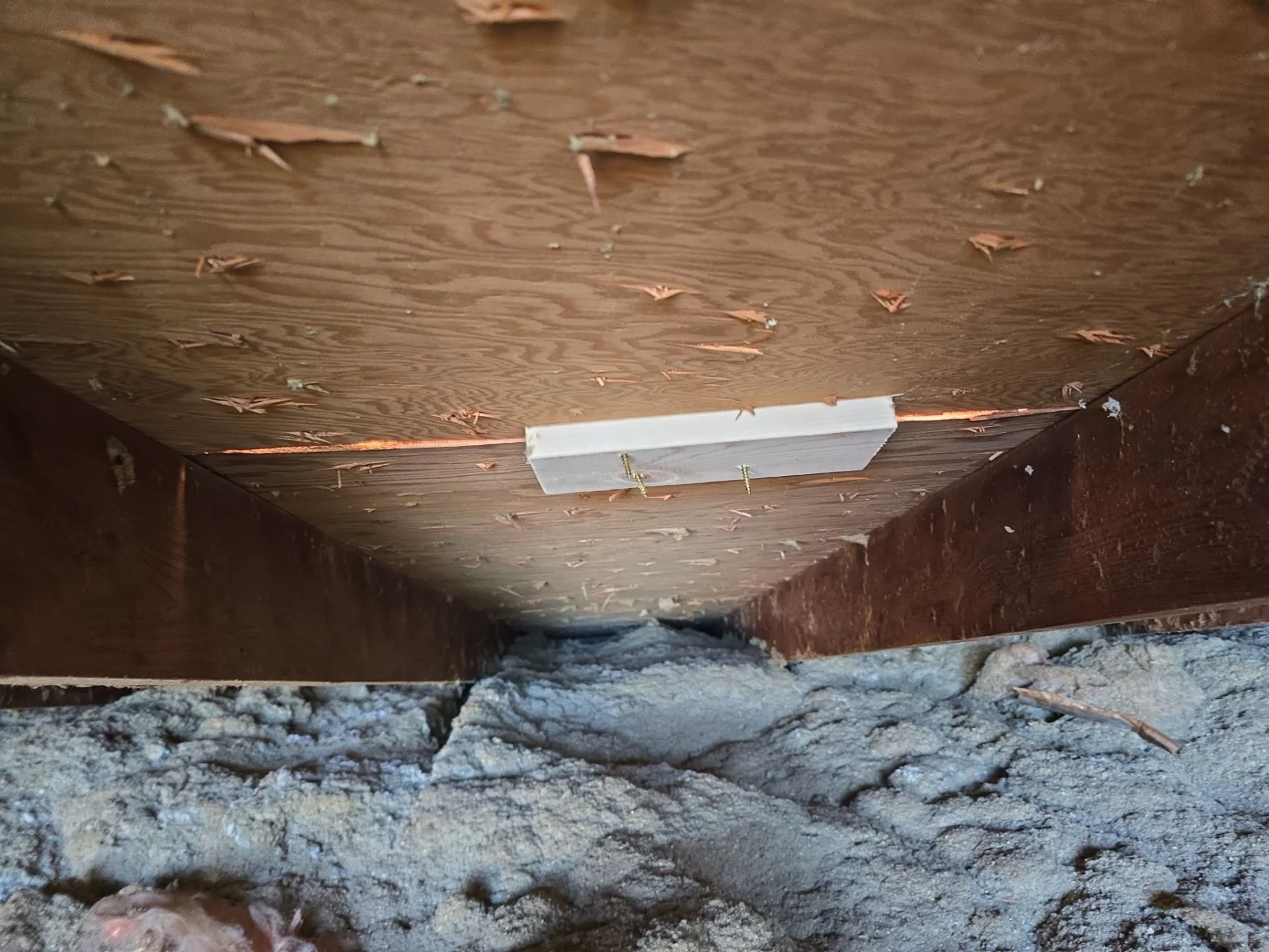 Buckle Down roofing cleat installed on roof decking from attic view, reinforcing structure for high wind resistance and storm protection
