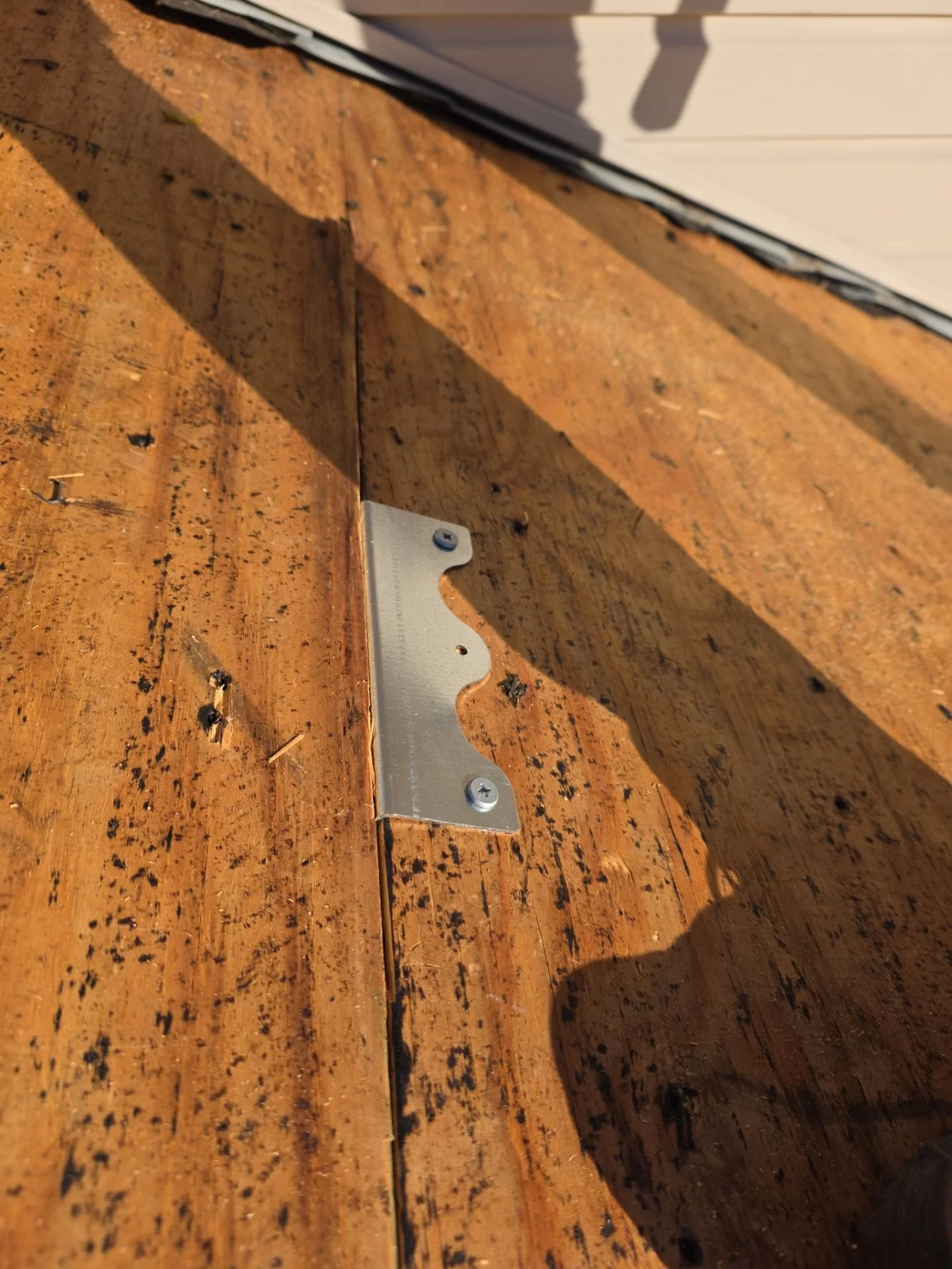 Roofing crew installing Buckle Down cleats across roof decking seams to strengthen structure and prevent movement under metal roofing panels