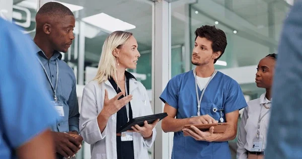 Healthcare professionals in discussion, including doctors and nurses, in a modern hospital setting.
