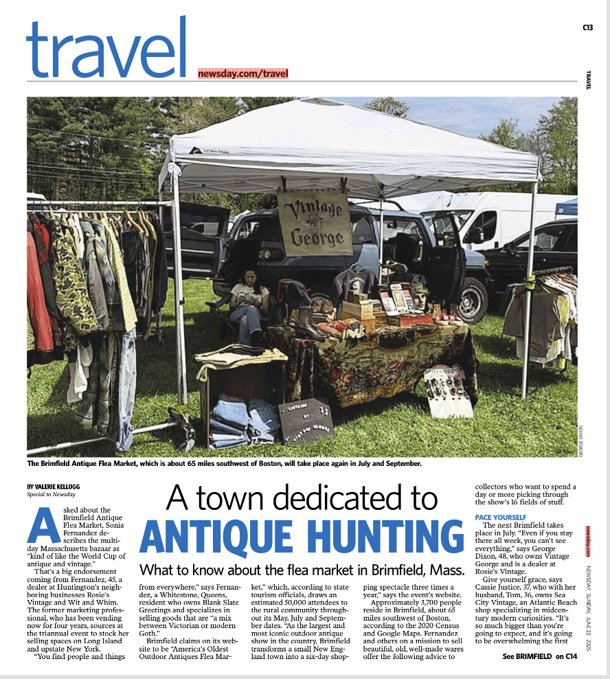 Photo of a flea market booth with vintage clothing and accessories, a sign that reads 'Vintage George,' and vehicles in the background.