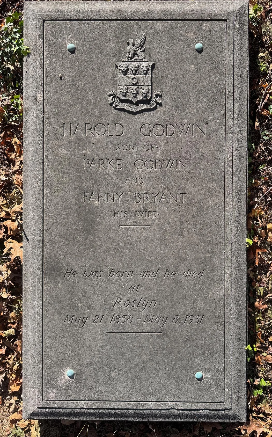A gravestone with a crest at the top, inscribed with the name Harold Godwin and details of his family and death, including dates of birth and death.
