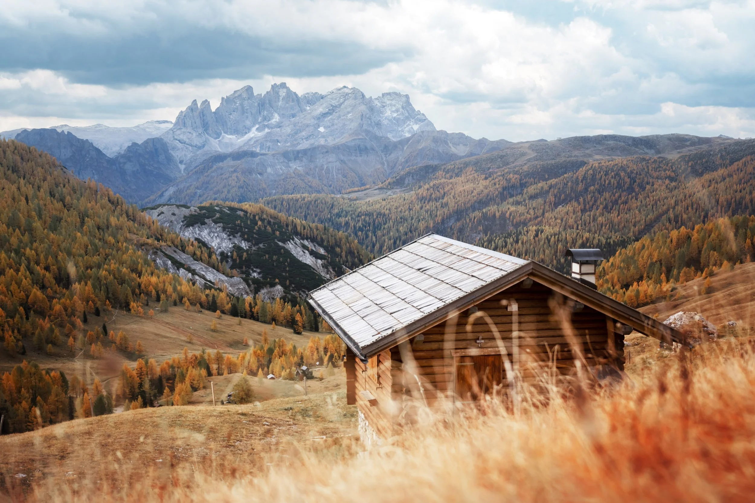 view from val fredda of the focobon and mulaz mountain group, fall couldy sky and autumn larch foliage surround the viewer