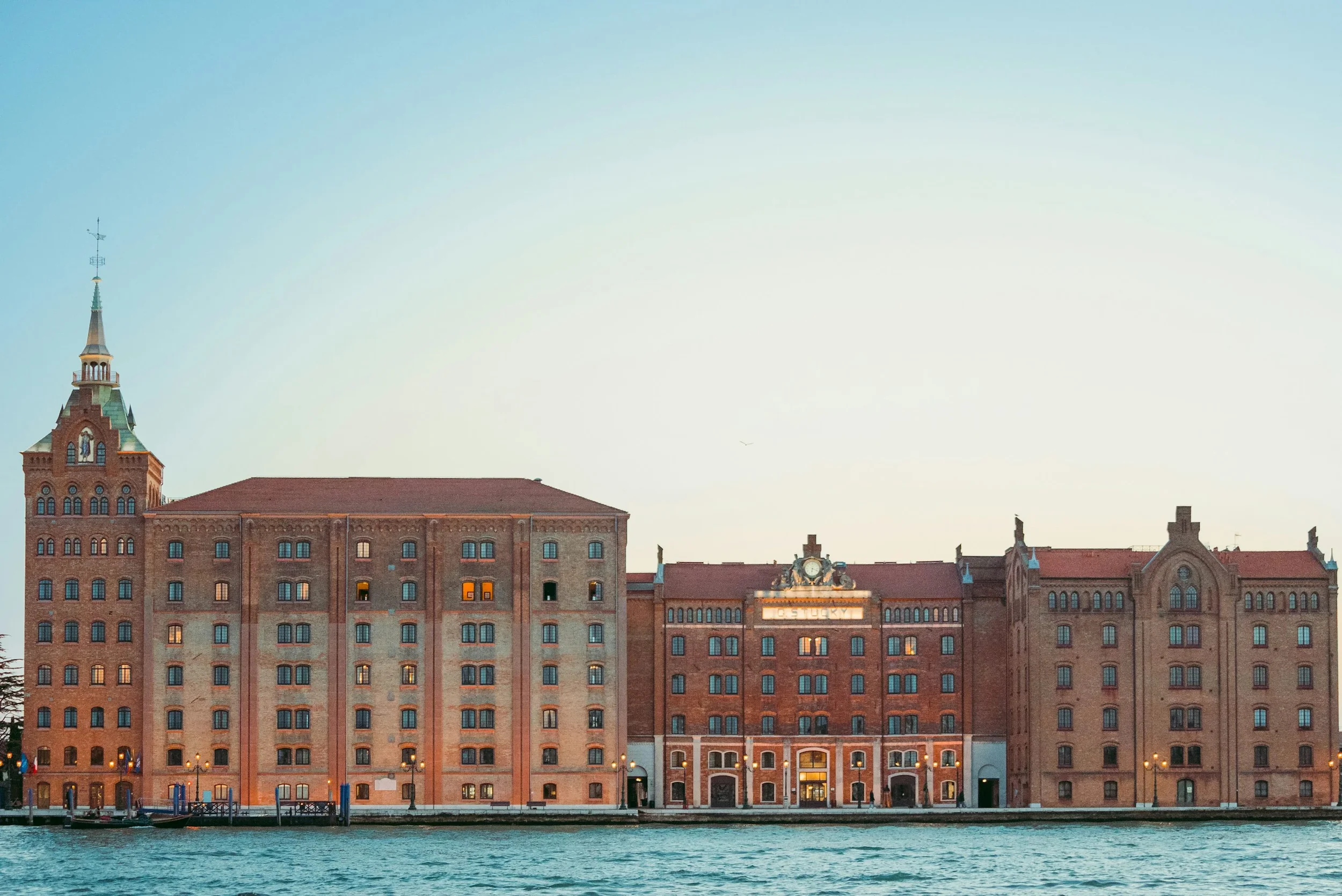 Historical red brick building along a river at sunset in Venice, Italy.