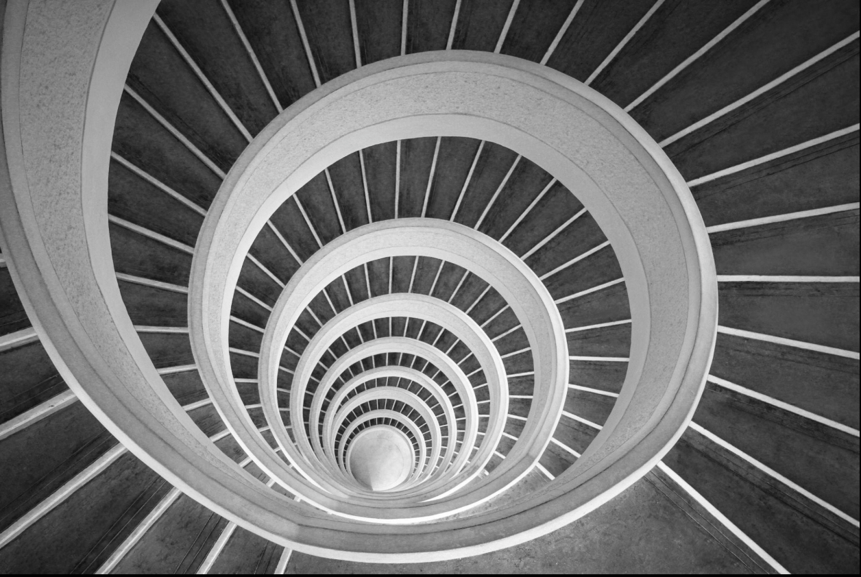 Black and white spiral staircase viewed from above, showing curved railings and steps.