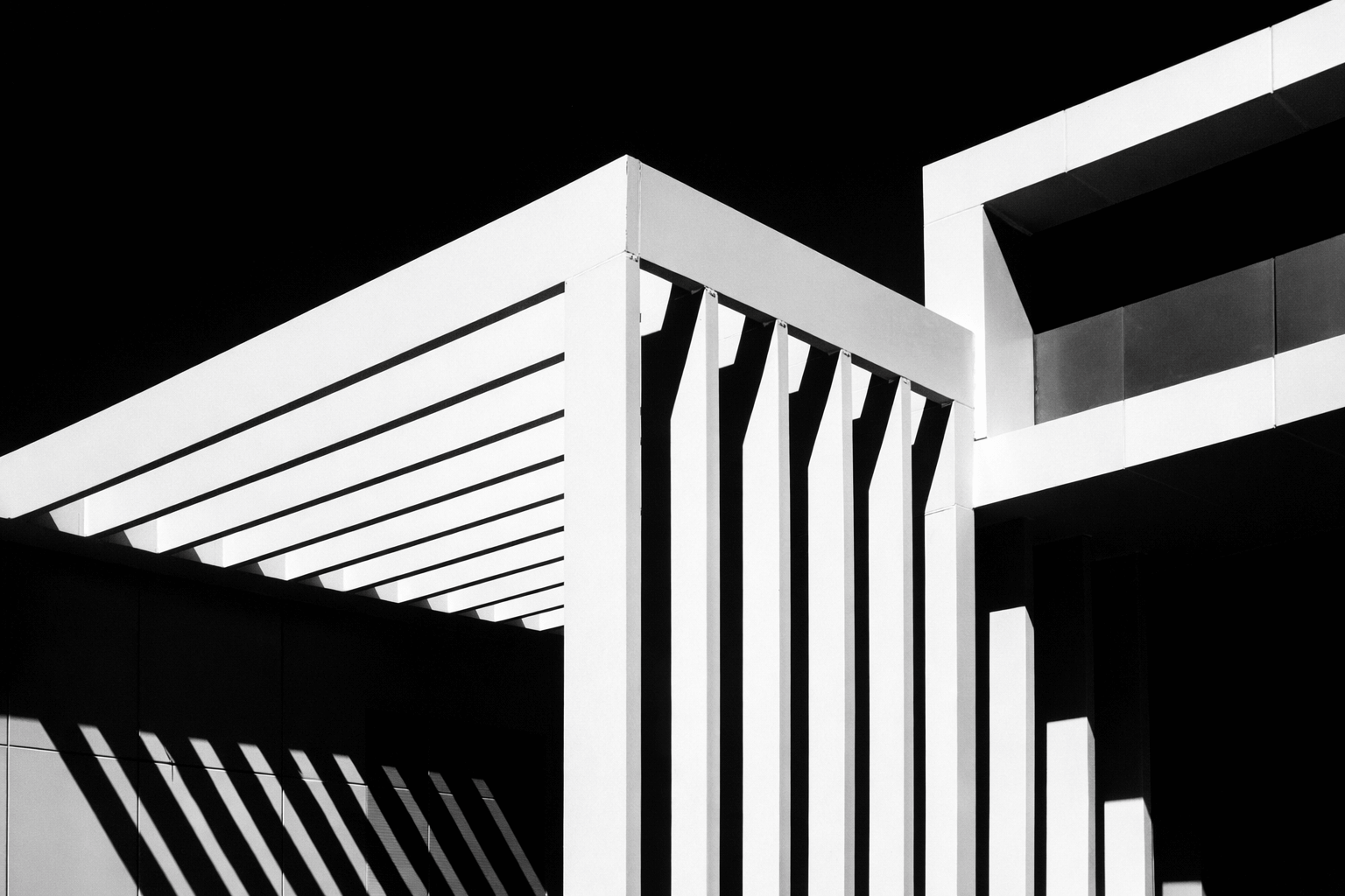 Black and white photo of a modern building with geometric architectural design, featuring horizontal and vertical lines and shadows.