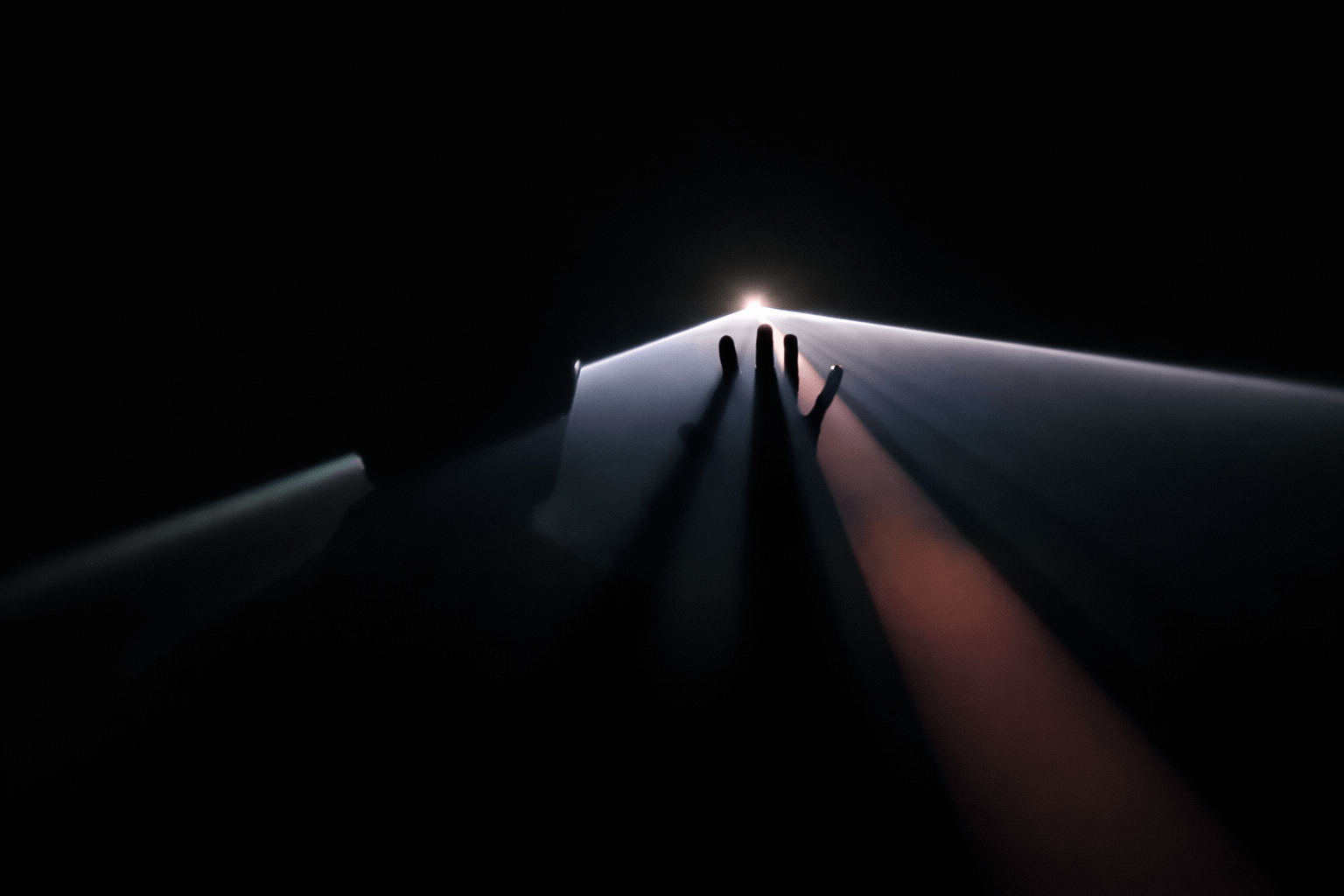 View of Earth's surface from space showing a dark landscape, illuminated by a small bright object, with a space shuttle or satellite's hand reaching towards the sunlight.