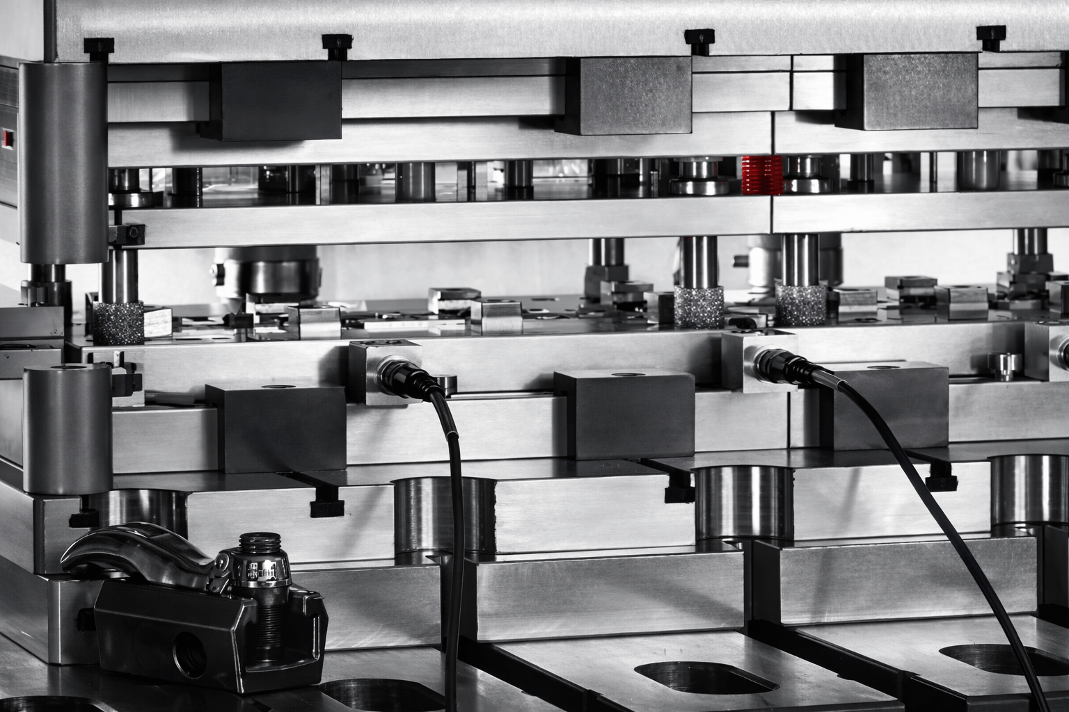 Close-up of a metallic industrial machine with various mechanical parts, wires, and a black telephone on the lower left side.