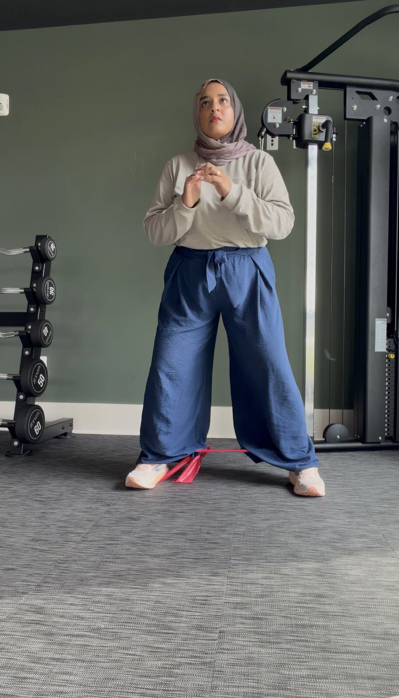 Woman in workout clothes on a resistance band exercise in a gym.