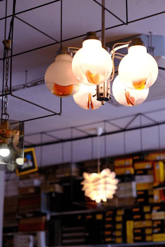 Lampi decorativi in vetro bianco in un ambiente interno, con scaffali pieni di libri sullo sfondo.