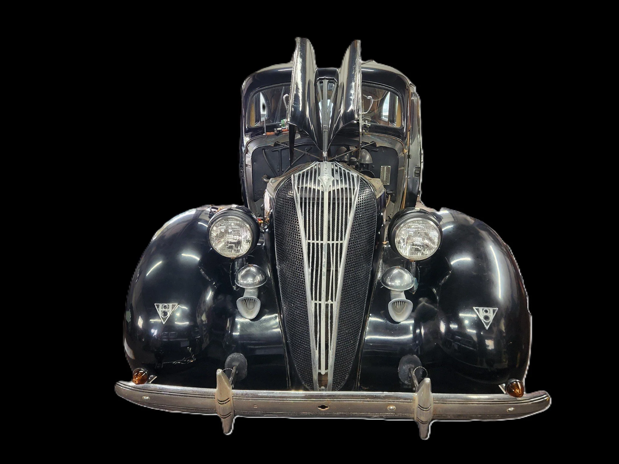Front view of a vintage black car with large round headlights, chrome grille, and rounded fenders.