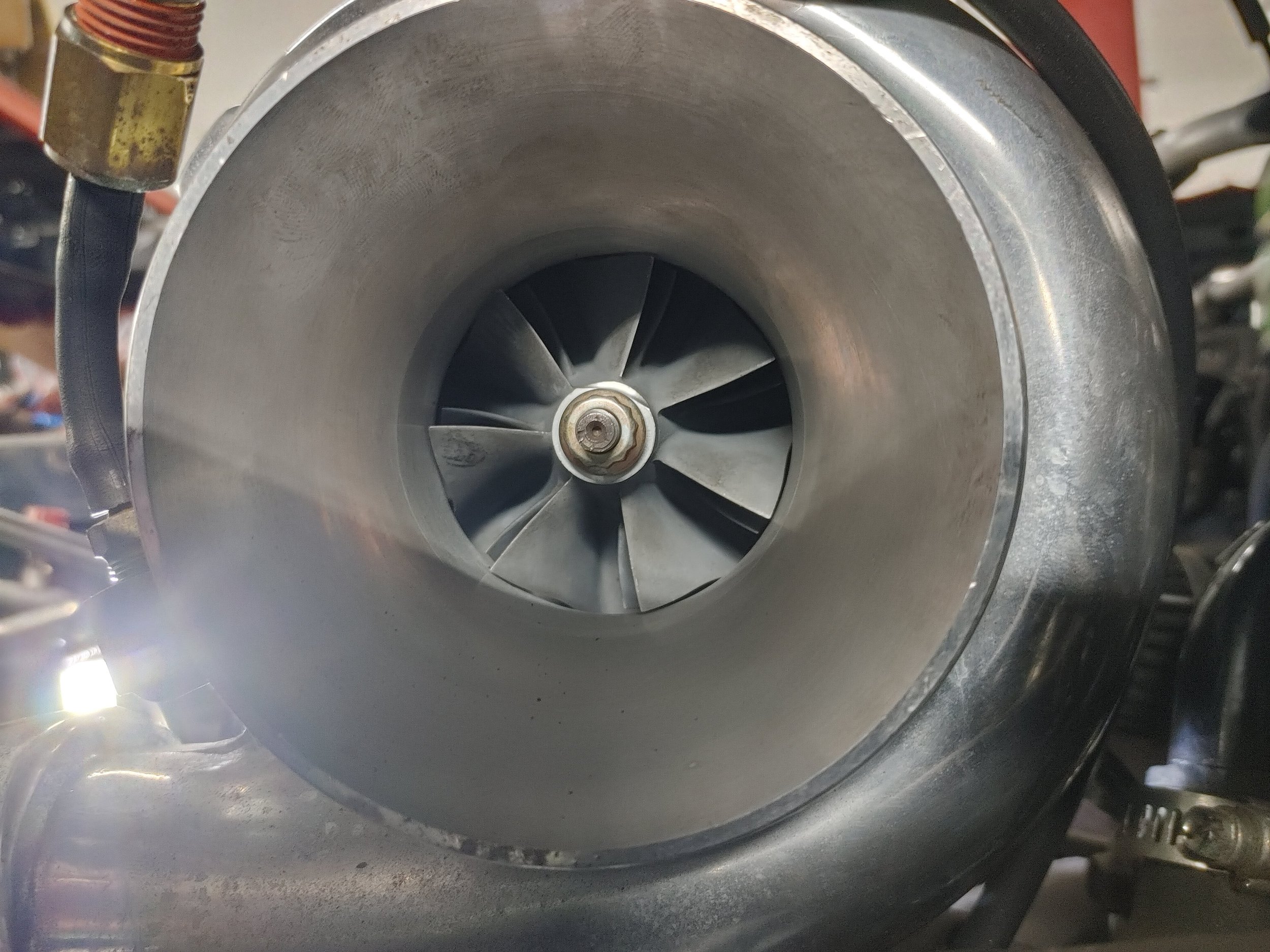 Close-up view of a turbocharger compressor wheel with multiple blades inside a metal housing.