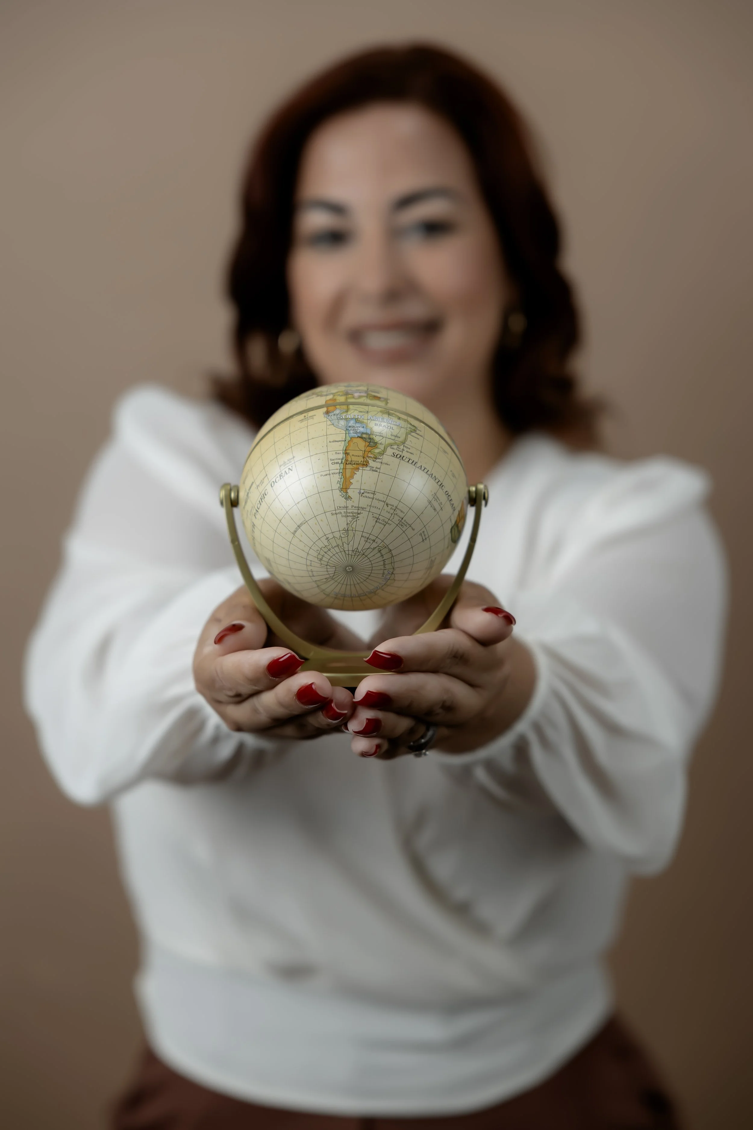 Woman holding a small globe with South America visible.
