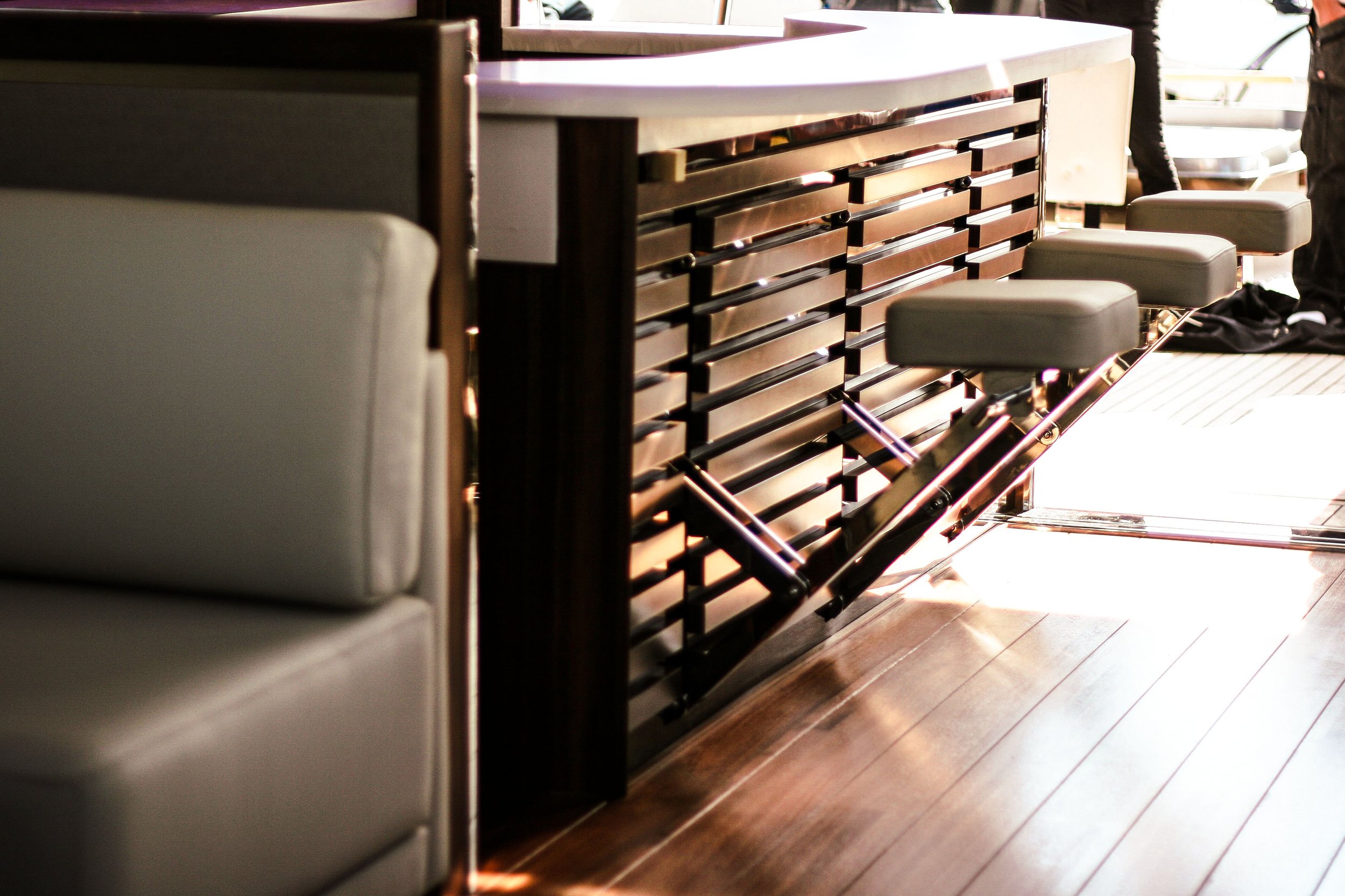 Indoor scene showing a bar with pull-out stools, a beige booth, and a wooden floor with sunlight streaming in.