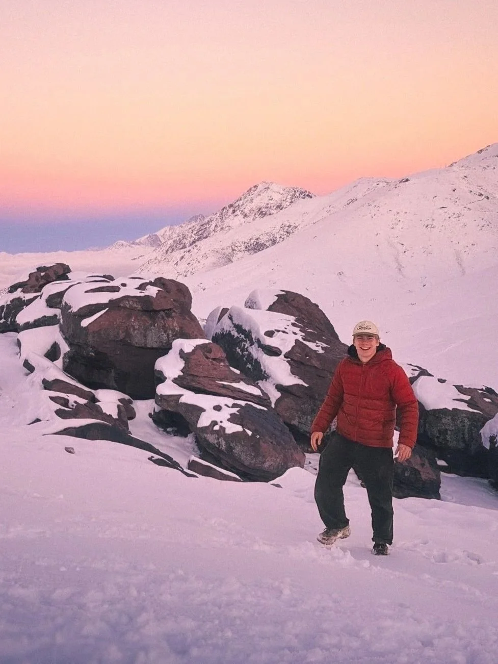 Jack high up in the Atlas mountains smiling in the snow before a beautiful sunset