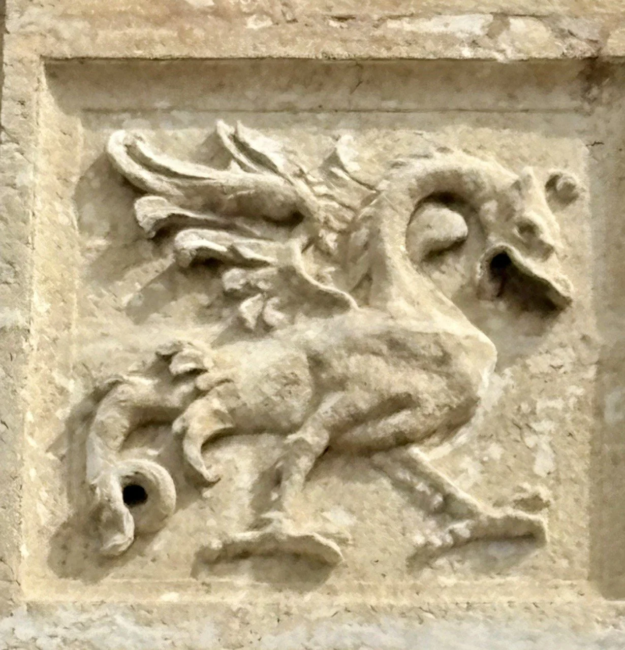 Stone carving of a dragon, facing right with an open mouth.