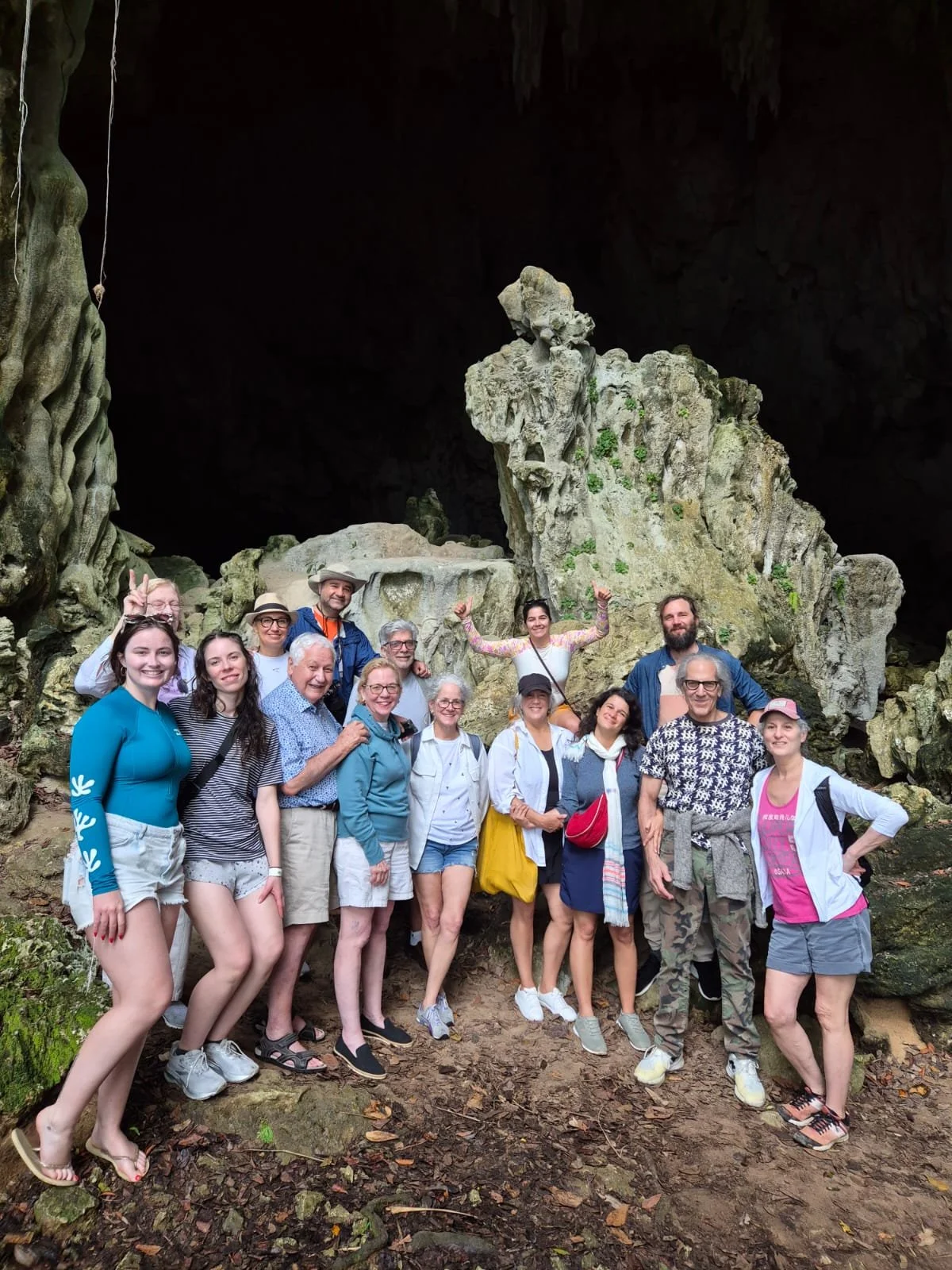 Group of people posing inside a cave with large rock formations in the background.