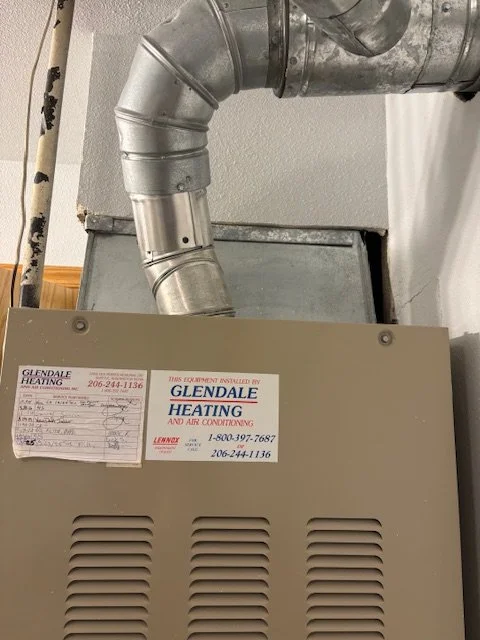 Close-up of a heating and air conditioning furnace with metal ductwork, labeled with a Glendale Heating and Air Conditioning sticker.