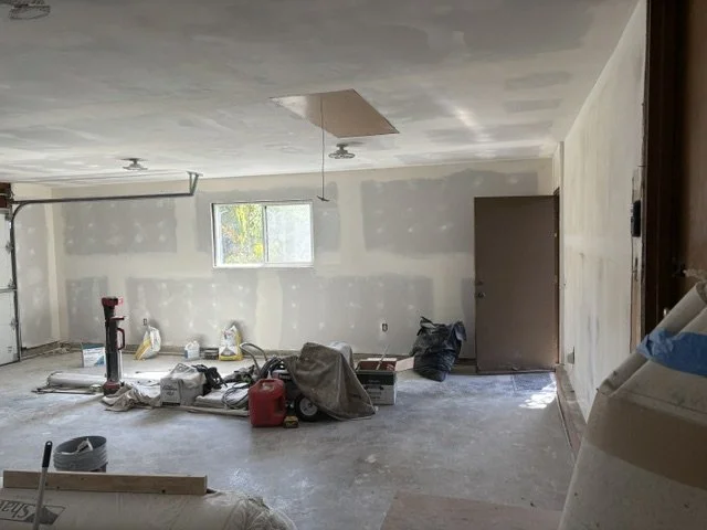 Unfinished room with drywall, construction tools, supplies, and a window.