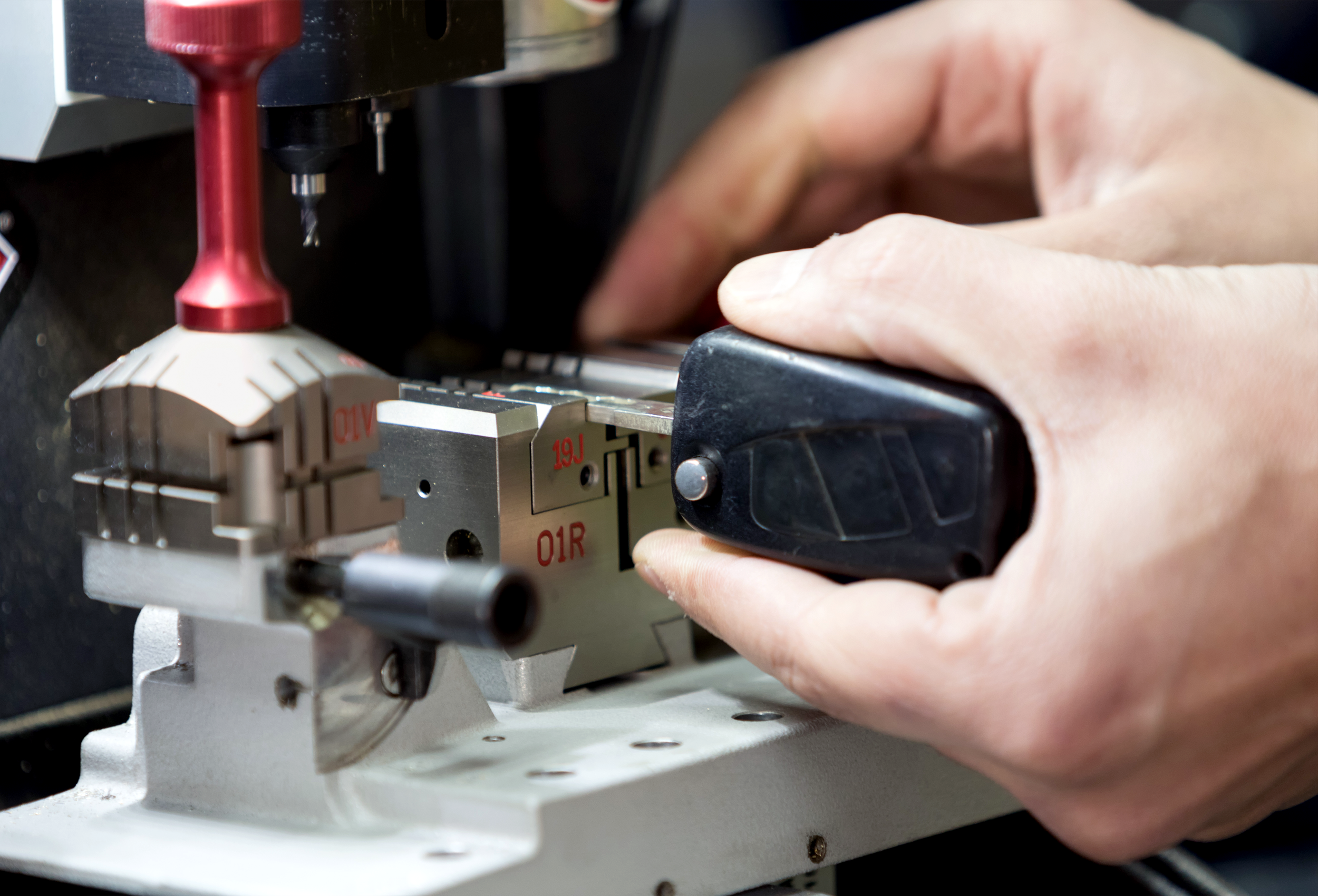 Close-up of a person's hand operating a piece of machinery with a black control button.