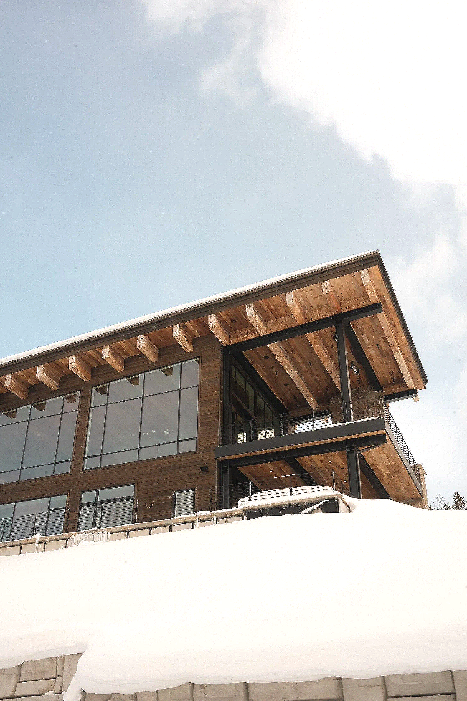 Modern wooden house with large glass windows on snowy landscape.