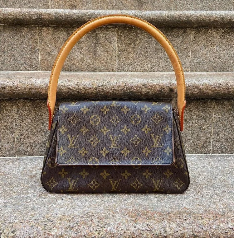 A Louis Vuitton handbag with the classic monogram pattern, placed on stone steps.