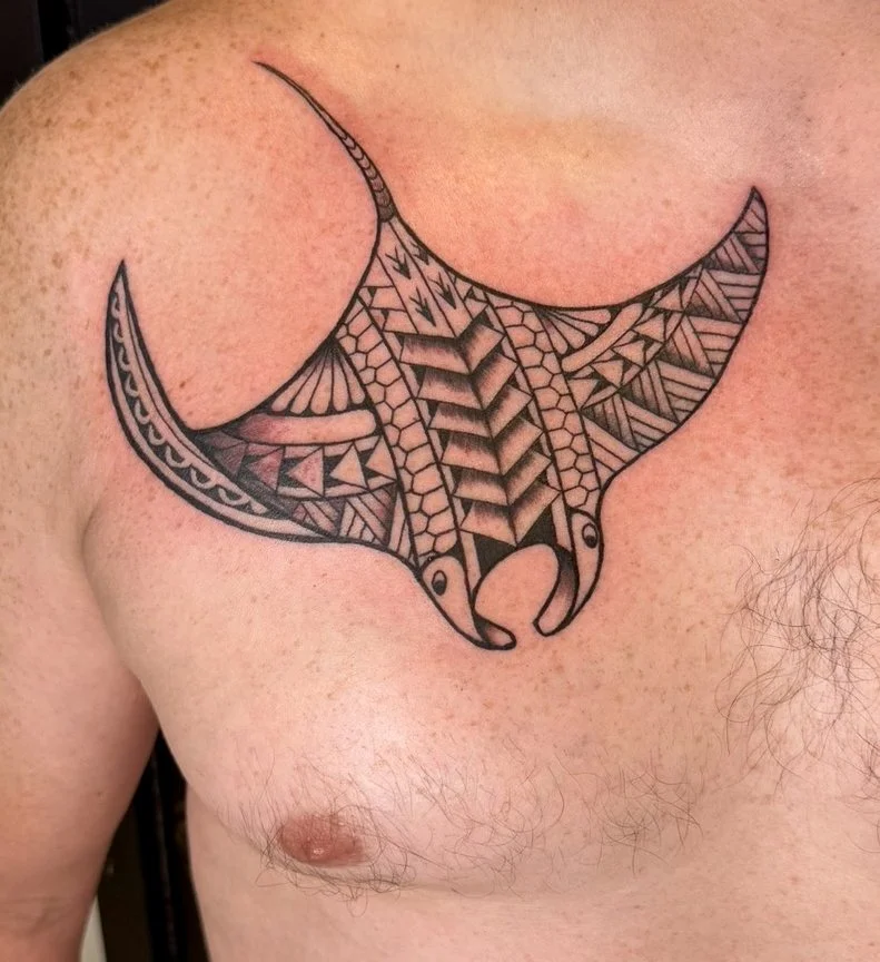 Black tribal-style tattoo of a bull's head on a person's upper chest, with geometric patterns on the horns.