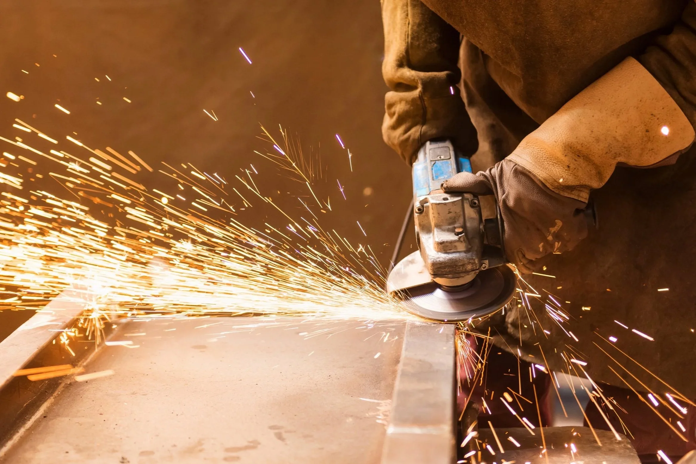 Someone using a disc grinder on a metal frame.