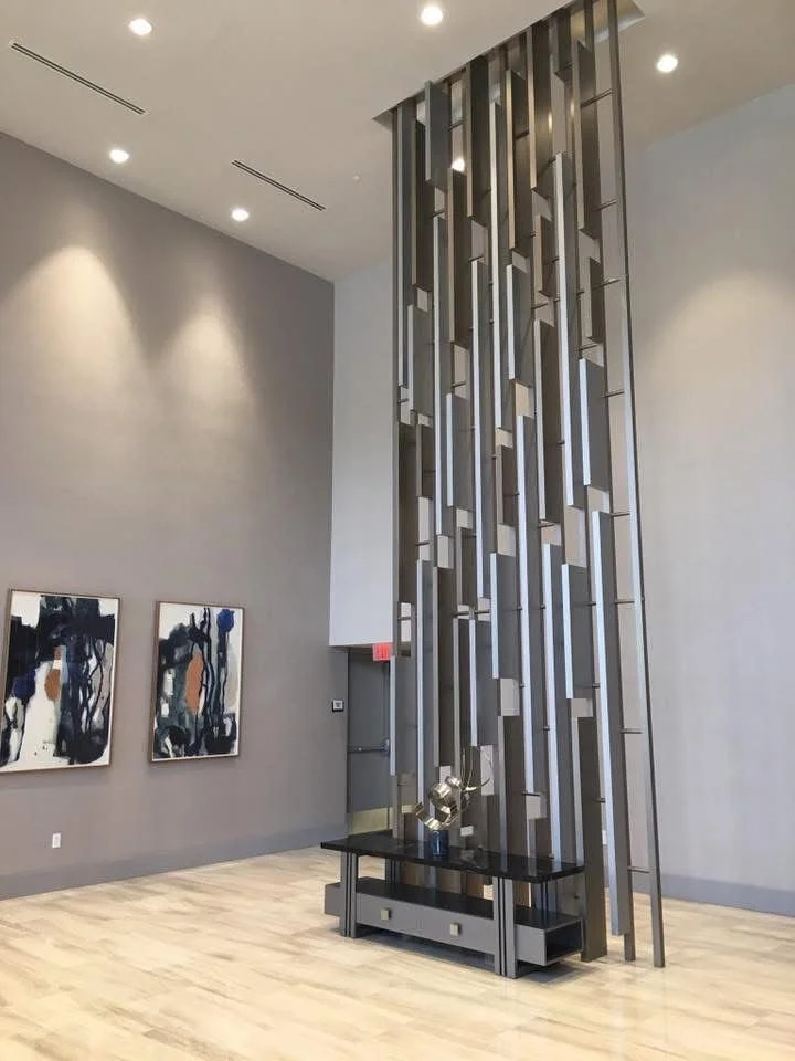 Modern interior with a large decorative metal sculpture and abstract wall art in a spacious, well-lit gallery or lobby area.