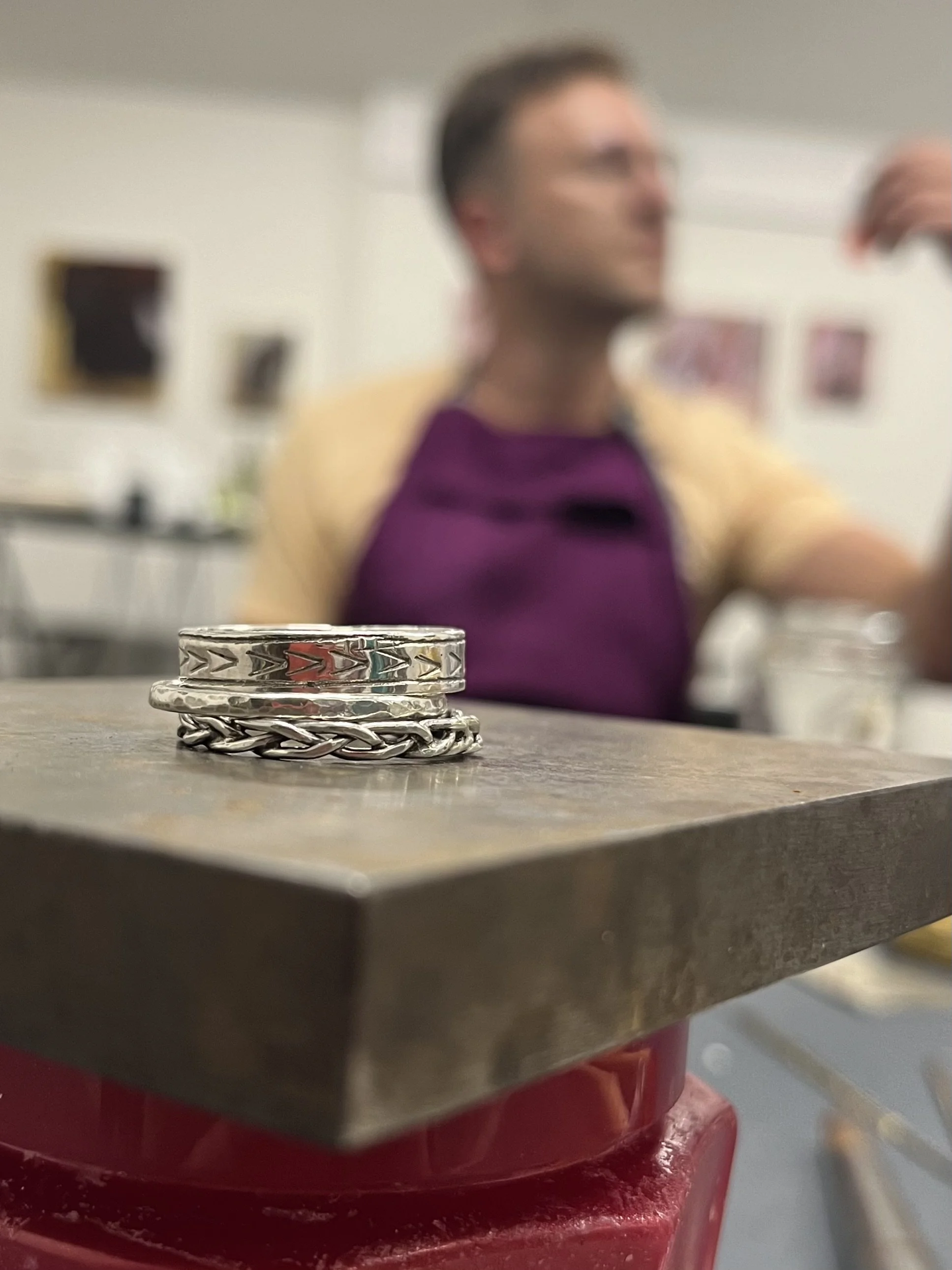 Close-up of layered metal rings on a table, with a blurred person in the background.