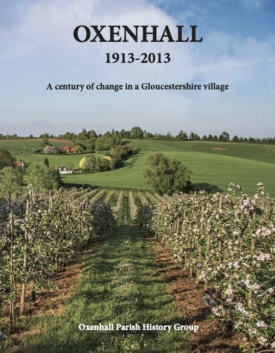 Photograph of a vineyard with rows of flowering vines and green hills in the background, overlaid with text about Oxenhall's 100 years of change from 1913 to 2013, organized by Oxenhall Parish History Group.