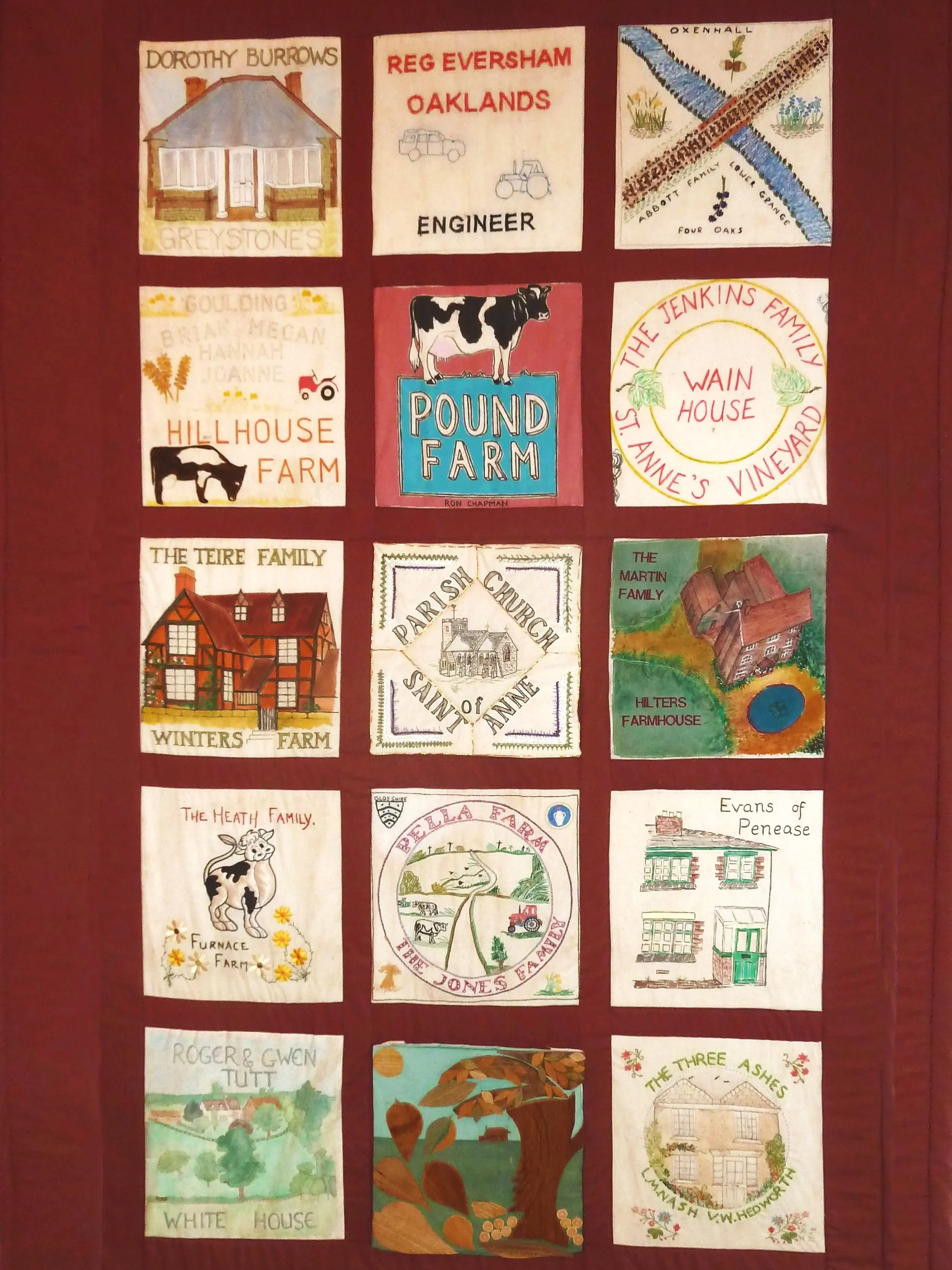 A quilt with a 12-square grid of embroidered and painted family farm houses, barns, and rural scenes, each labeled with family names and farm names.