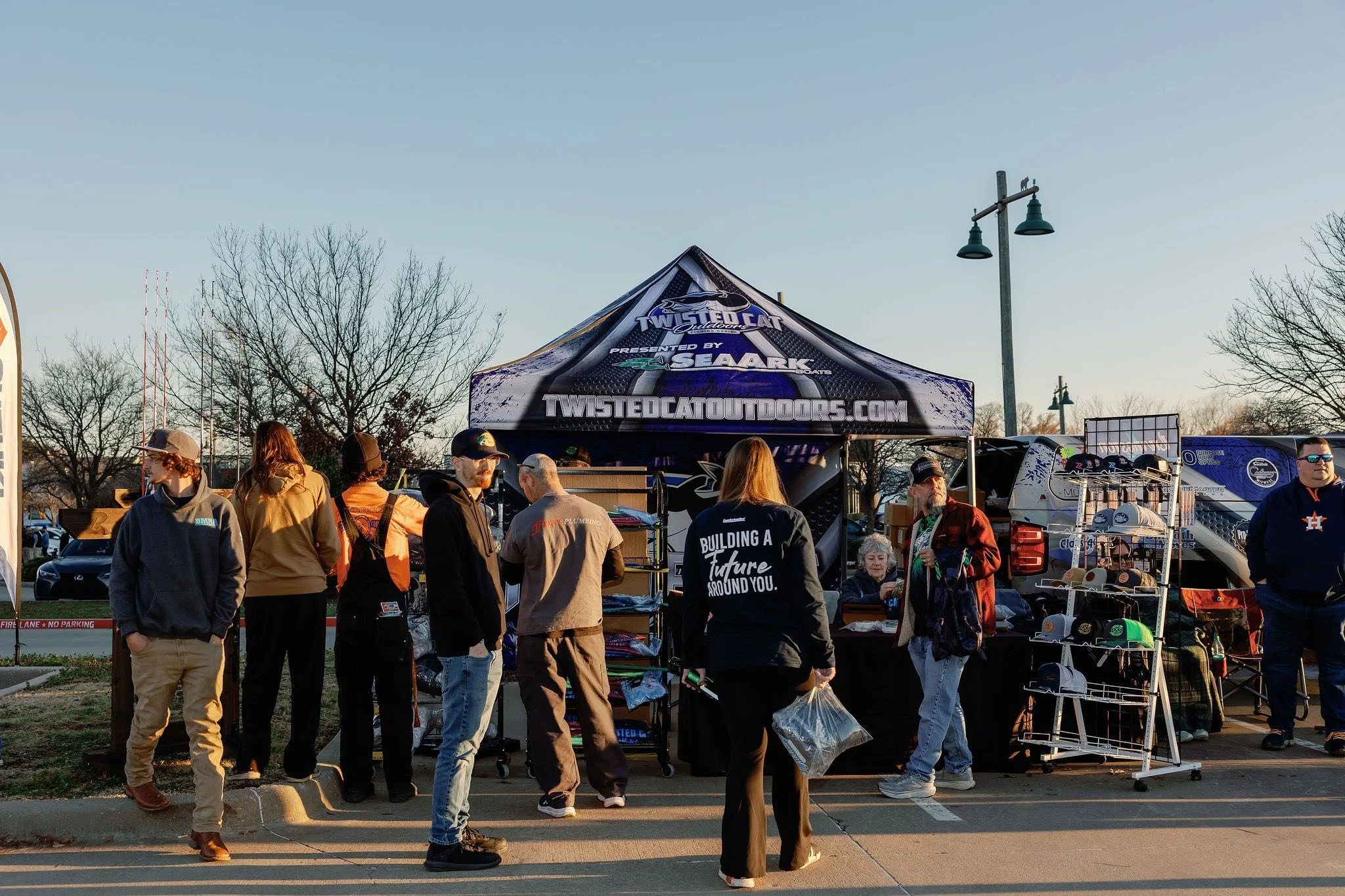 Large crowd of anglers around and under a tent at a Twisted Cat Outdoors event.
