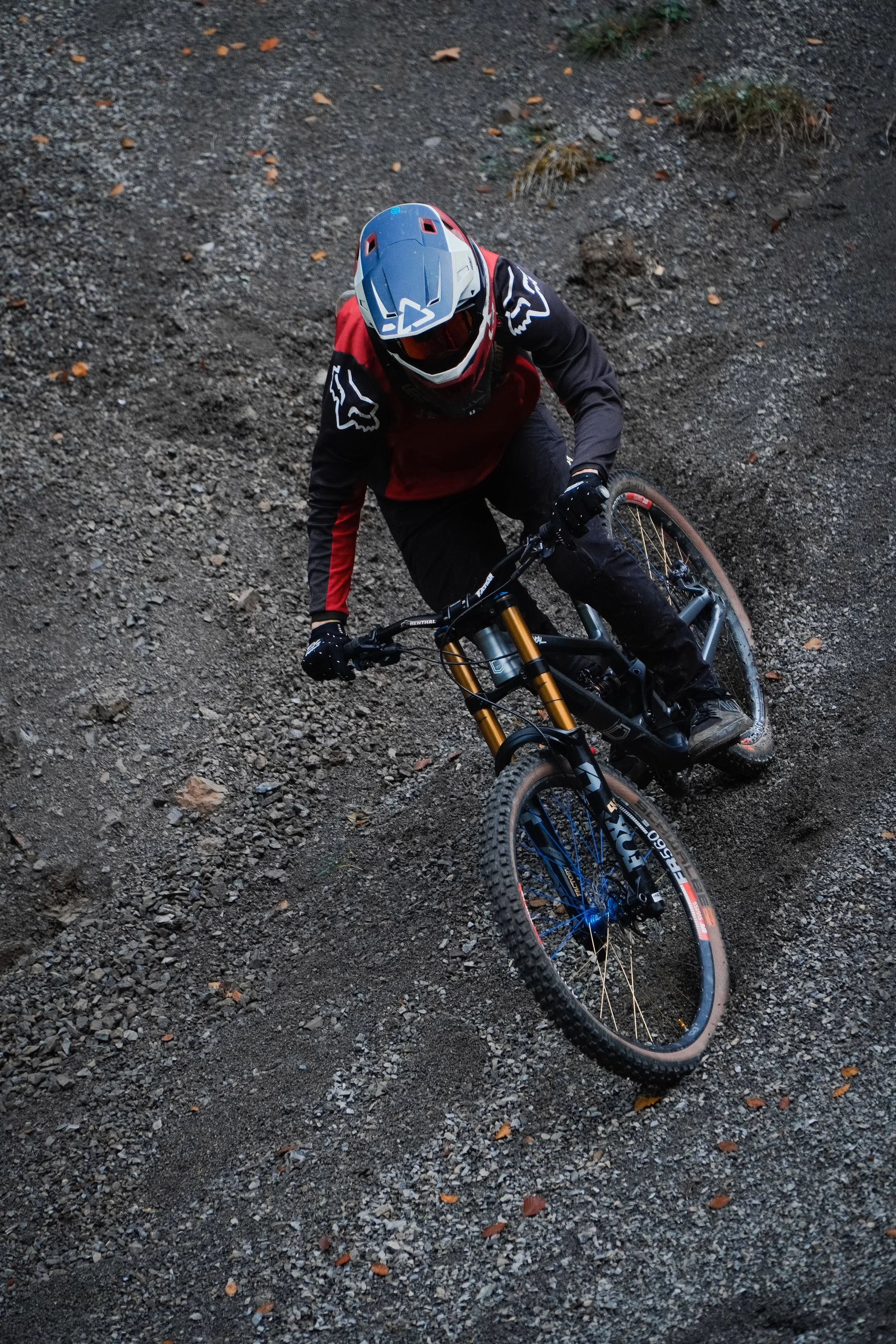 Mountainbiker beim Abfahrt auf einem schlammigen Pfad, getragen von einem Schutzhelm und sportlicher Kleidung.