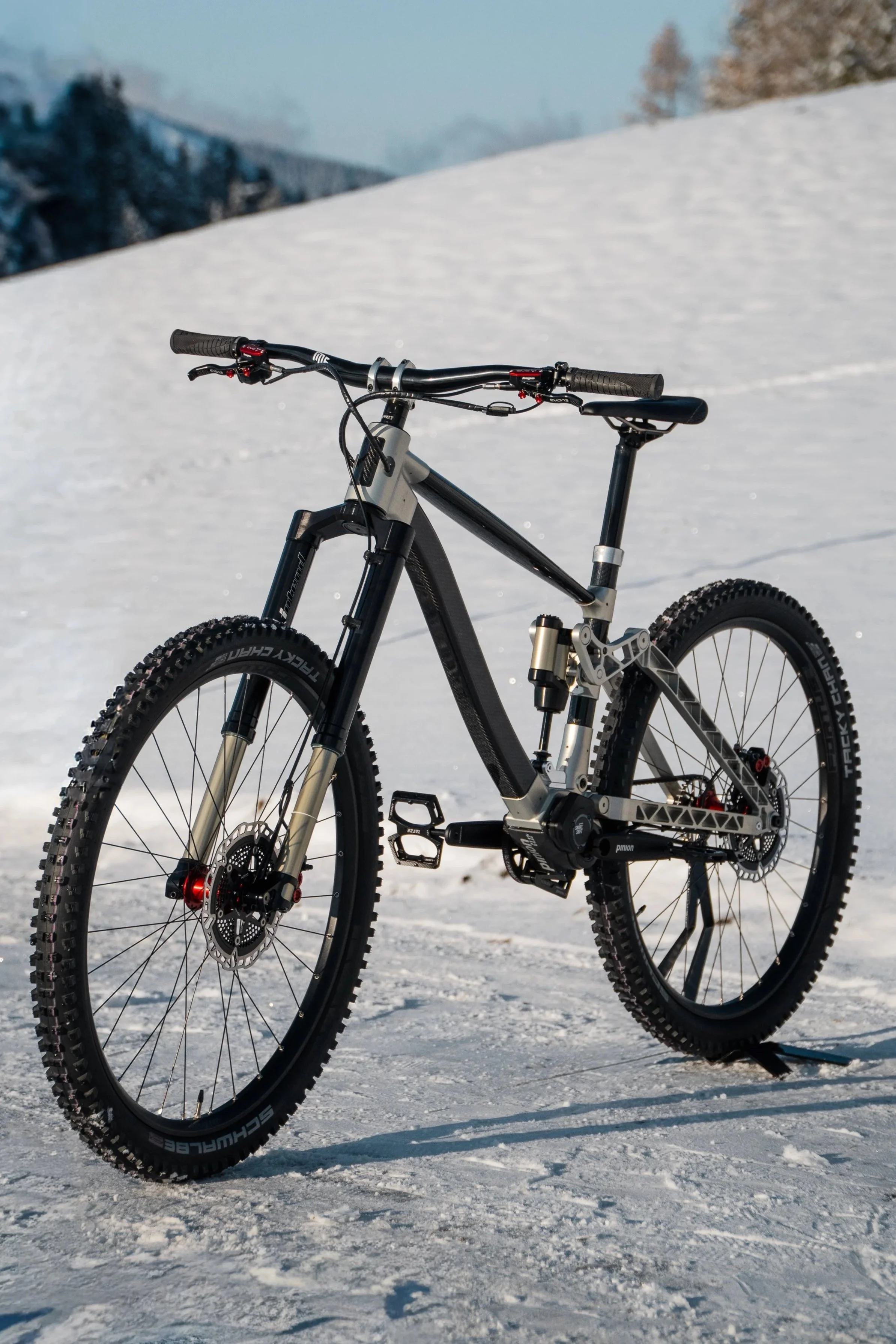 Ein modernes Mountainbike steht auf schneebedecktem Boden in einer winterlichen Berglandschaft.