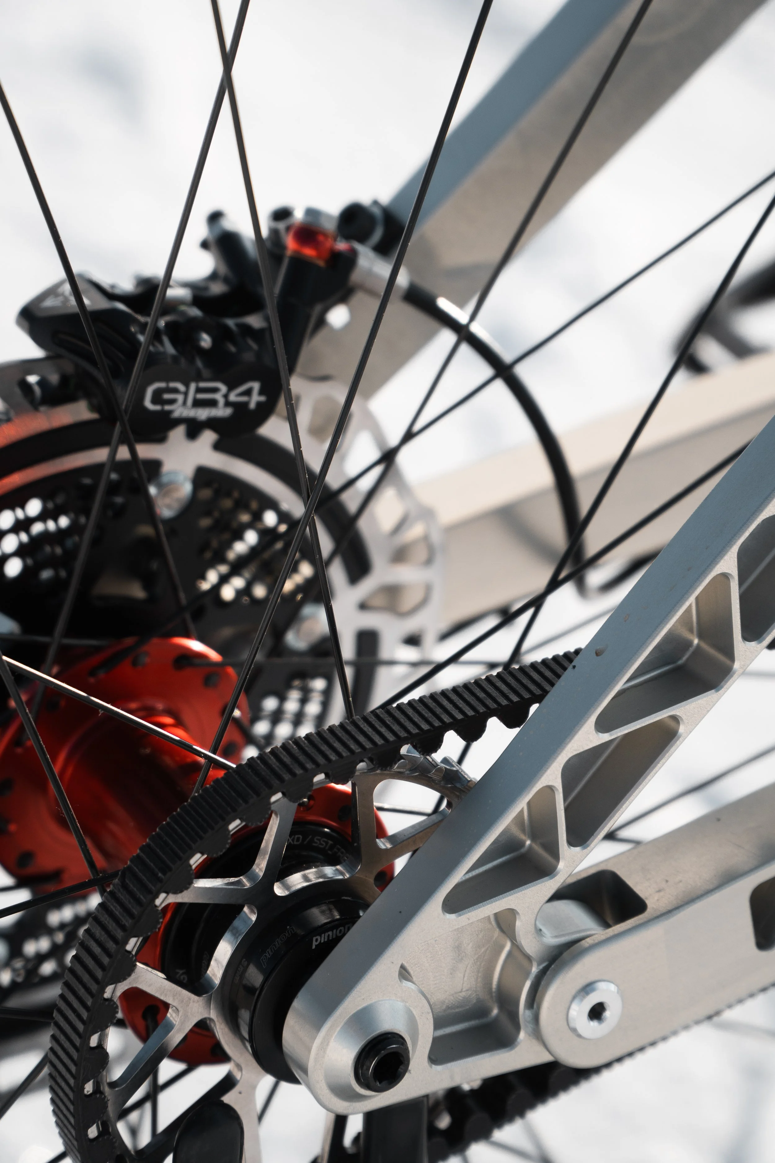 Nahaufnahme eines Fahrradnaben und Antriebskomponenten, einschließlich Kette und Kassette, vor einem weichen, weißen Hintergrund.