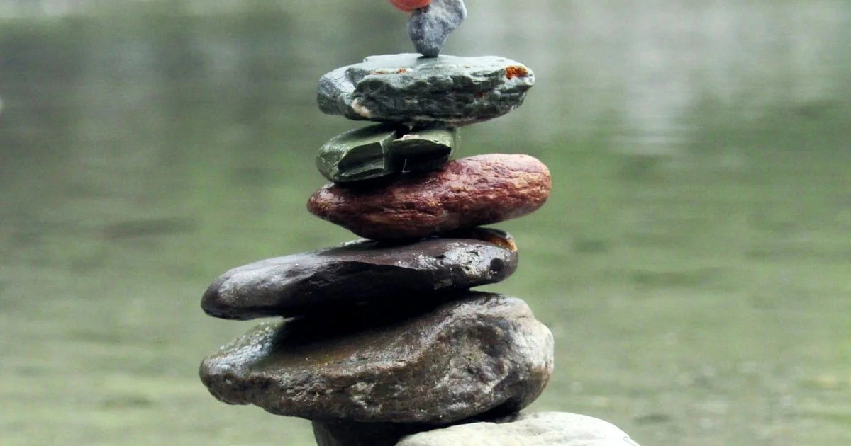 Eine Steinmauer mit mehreren übereinander gestapelten glatten Steinen in einem Wasserfluss.